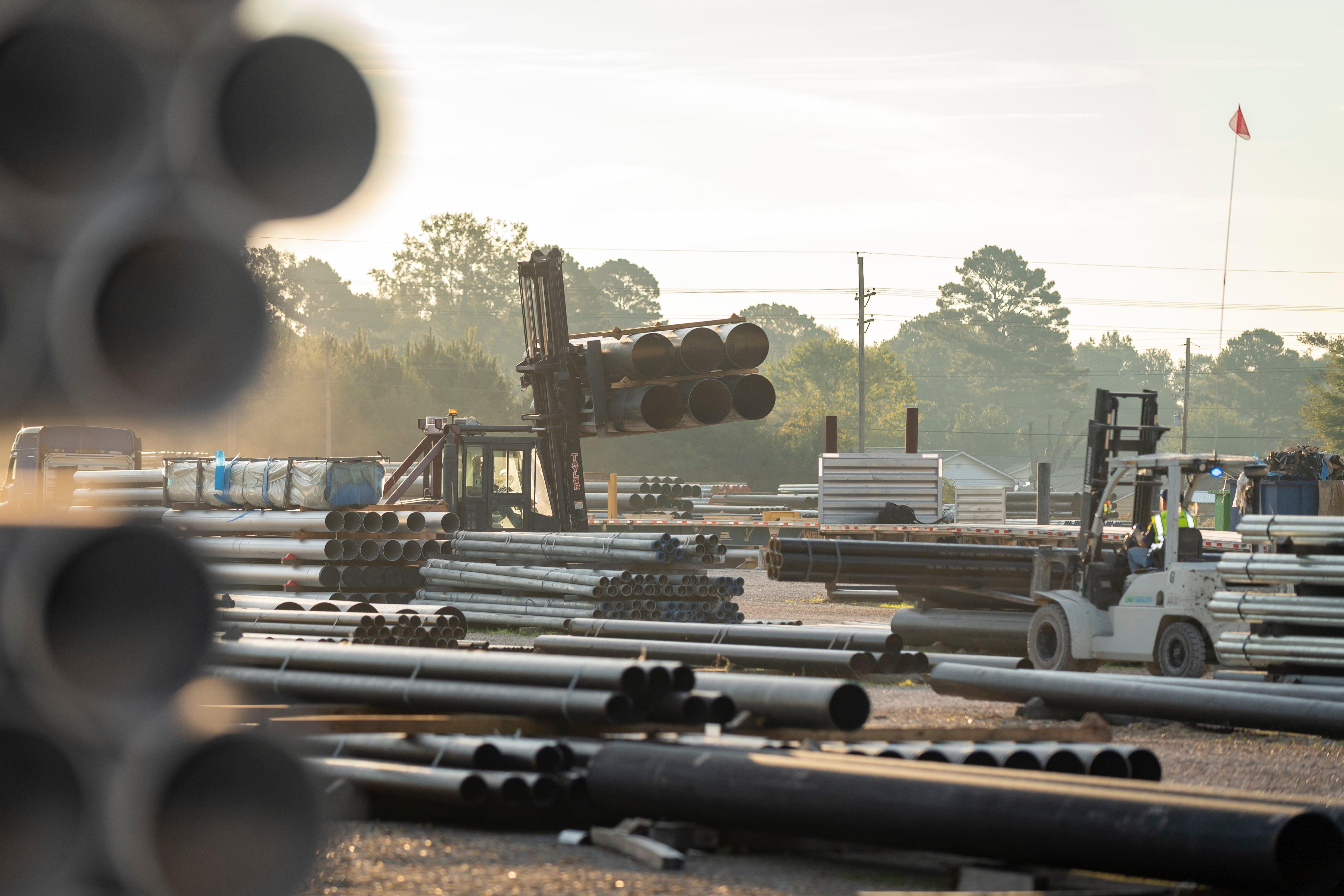 On a jobsite, a front-end loader hauls a stack of pipe.