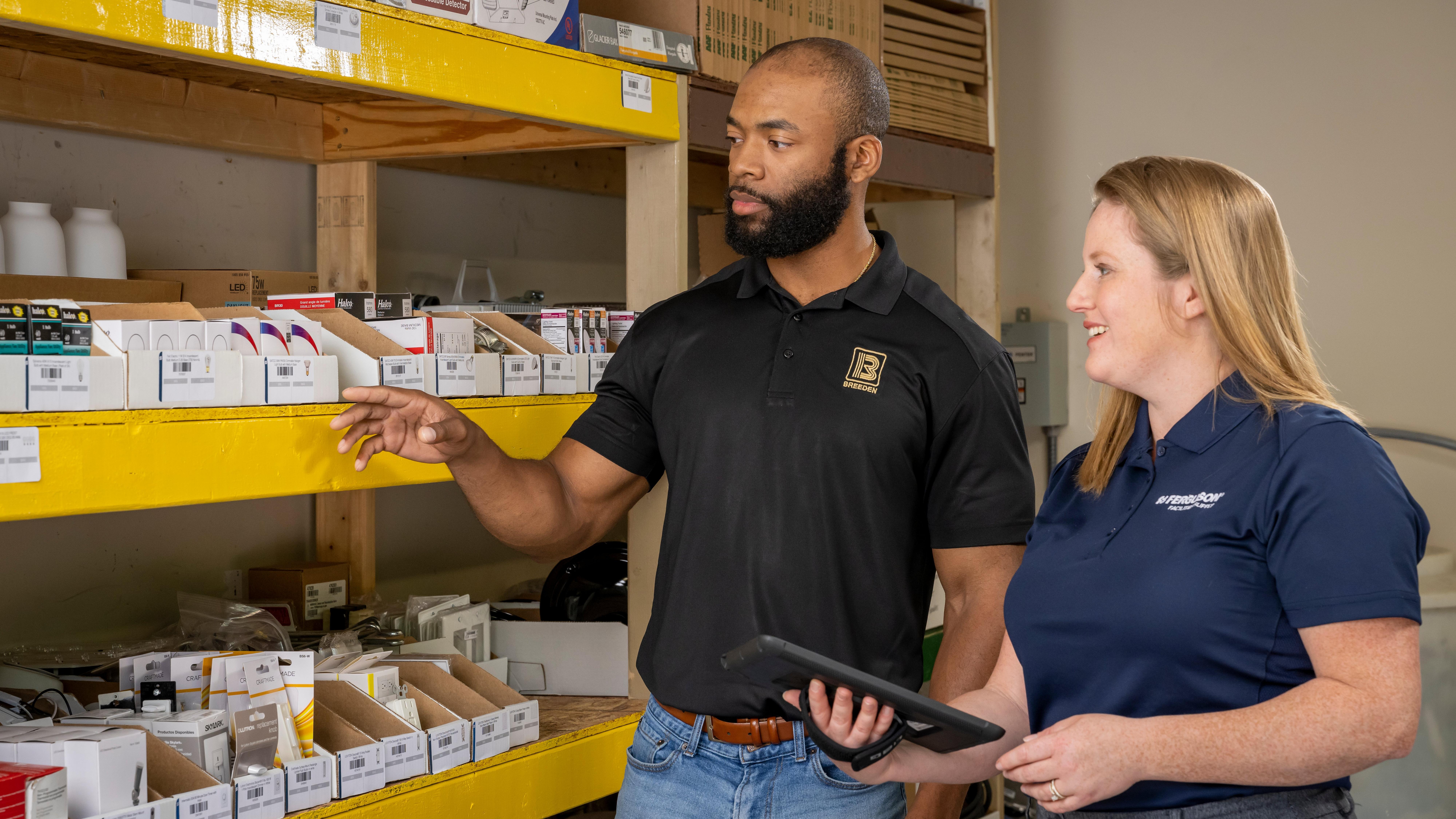 A Ferguson associate helps a facilities supply worker review his inventory on wooden shelves.