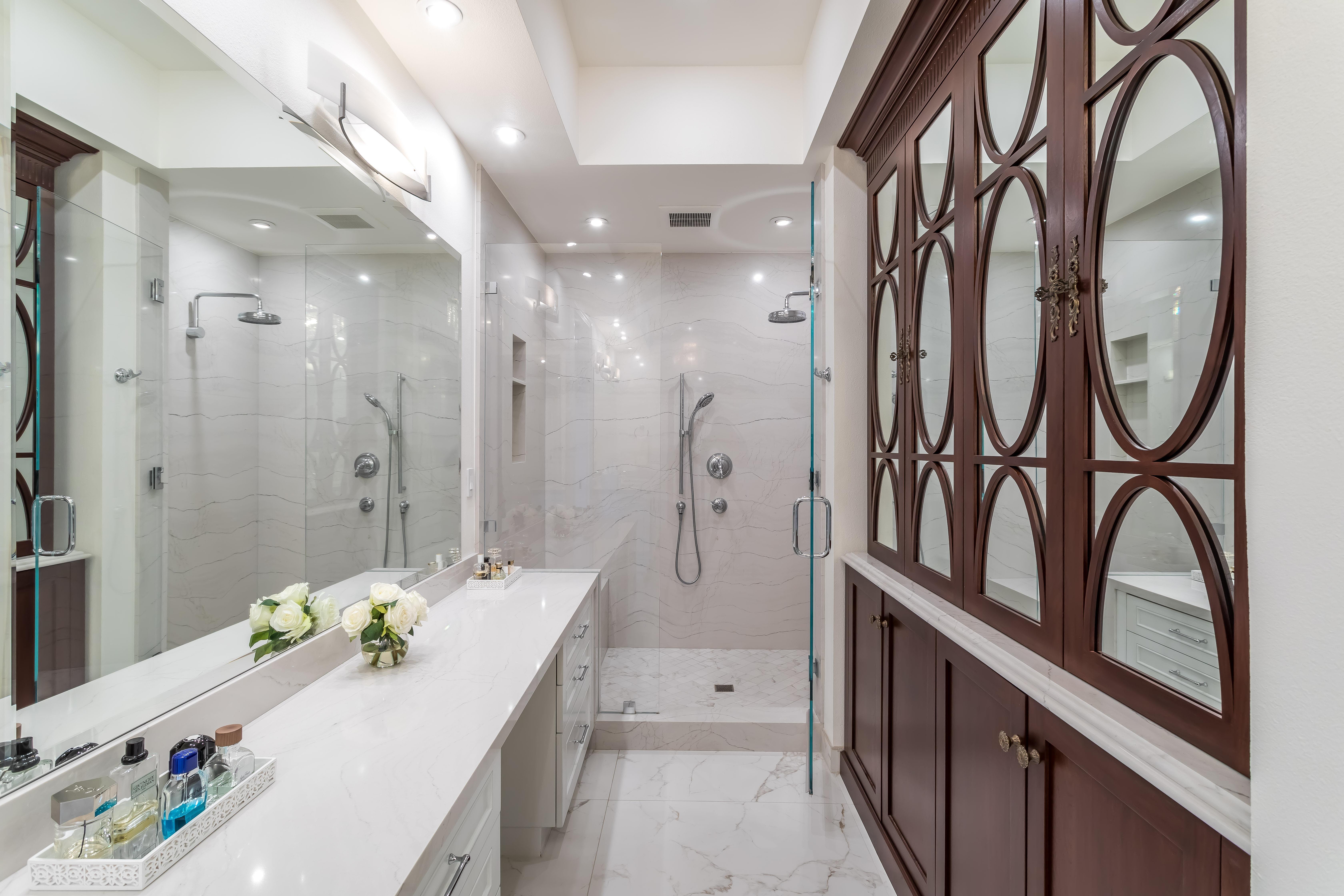 A white bathroom with walk-in shower and mirrors on the right.