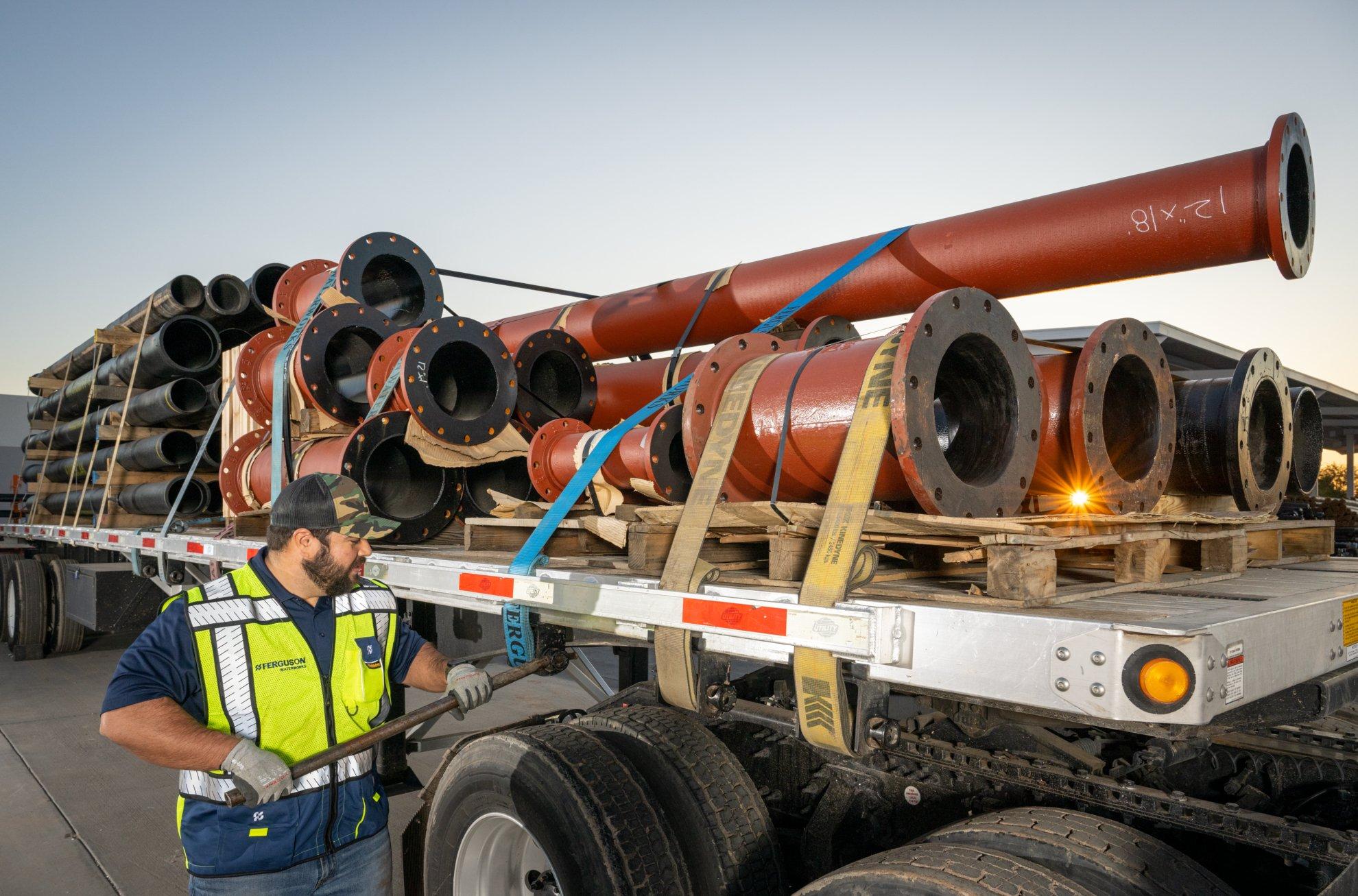 A Ferguson associate secures pipe onto a truck flatbed for delivery.