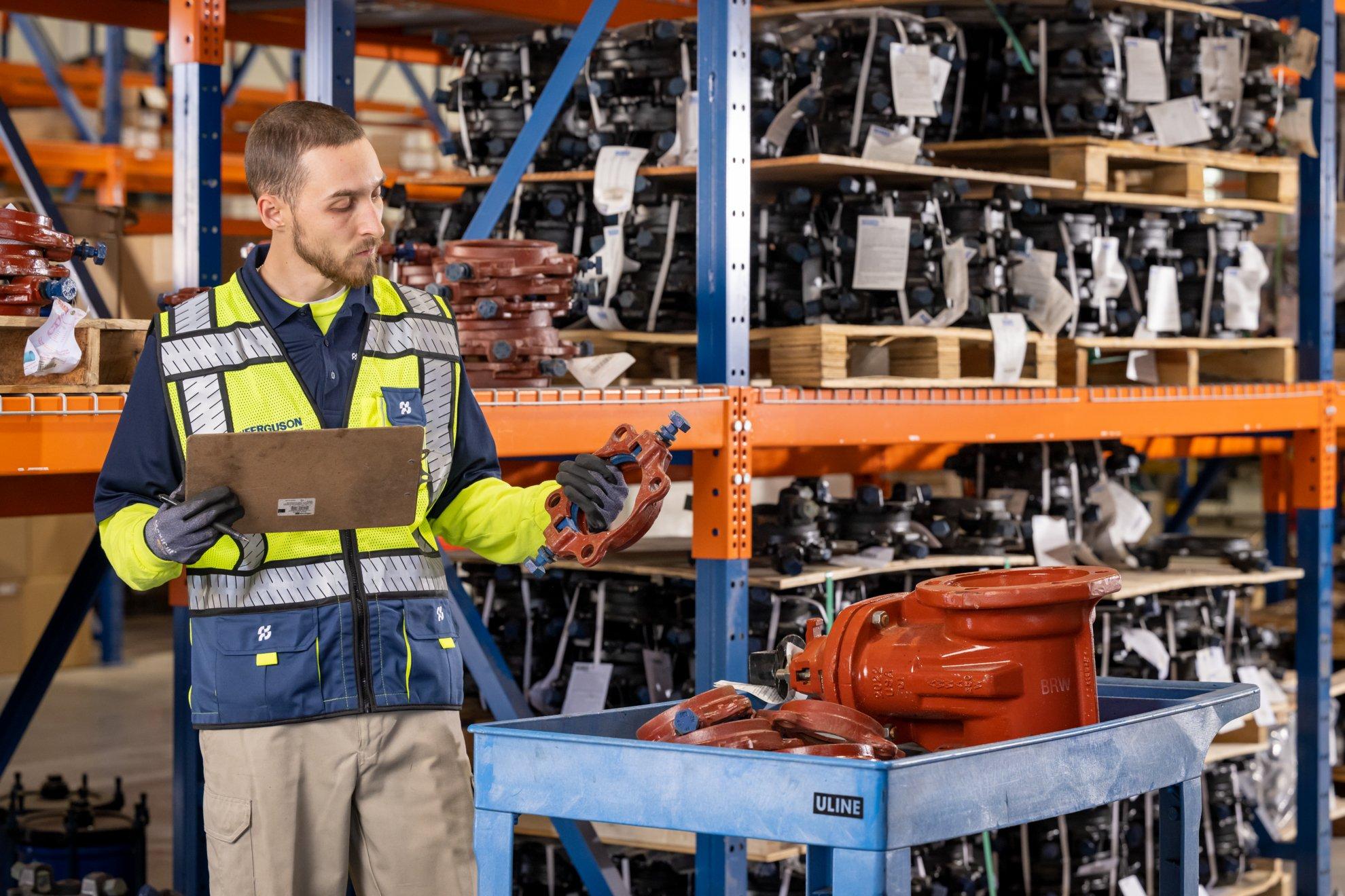 A Ferguson associate examines pipe valves in a distribution center.