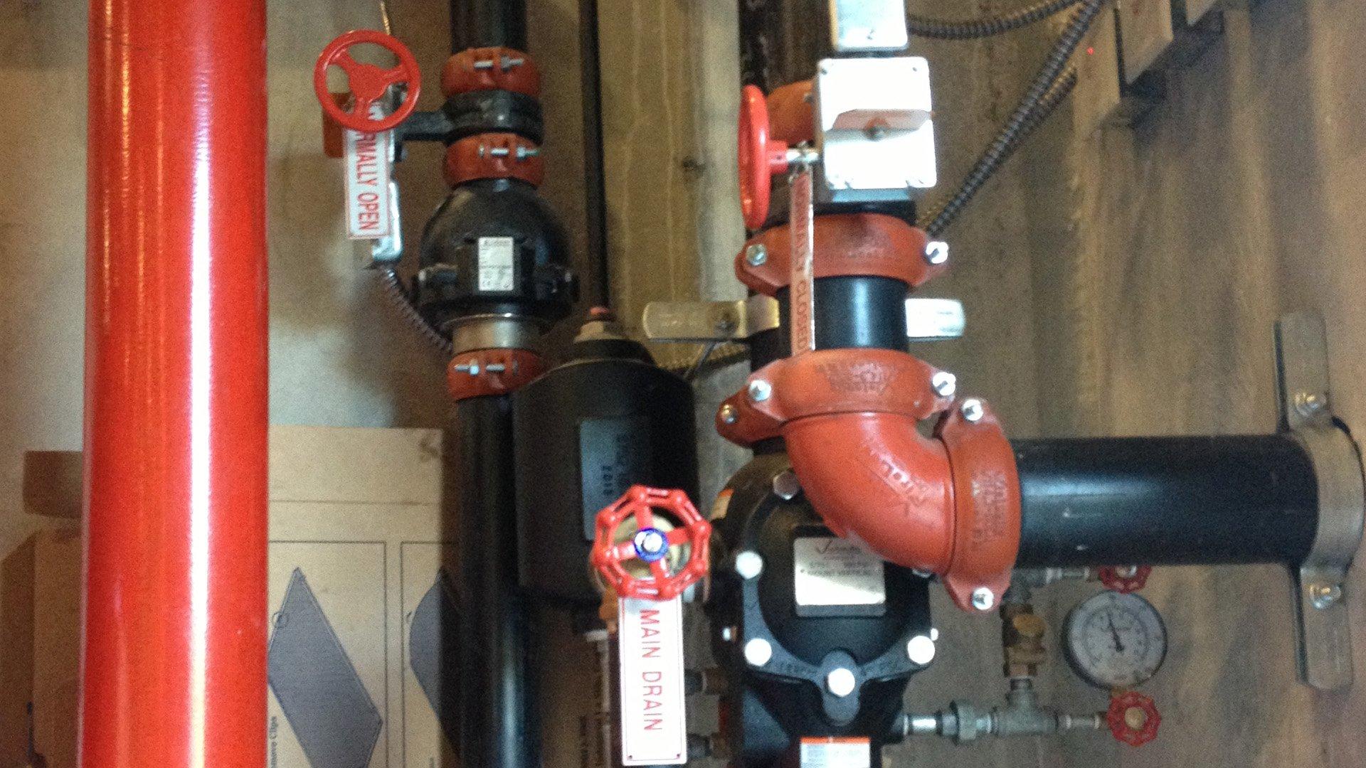 Various red and black pipes with valves and safety hanging tags.