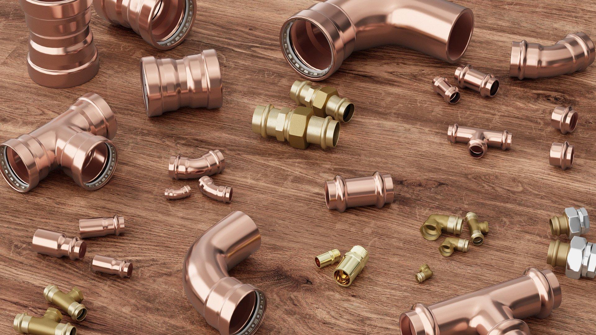 FNW copper press fitting in multiple sizes displayed on a wooden table.