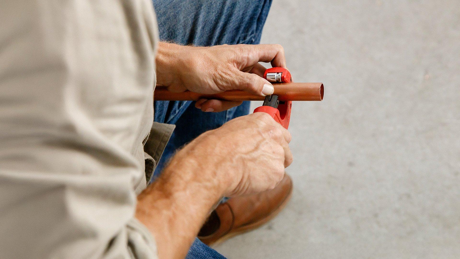 Close up image of plumber cutting a copper pipe.