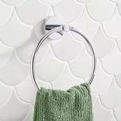 A green hand towel on a round silver towel holder against a white tile background.