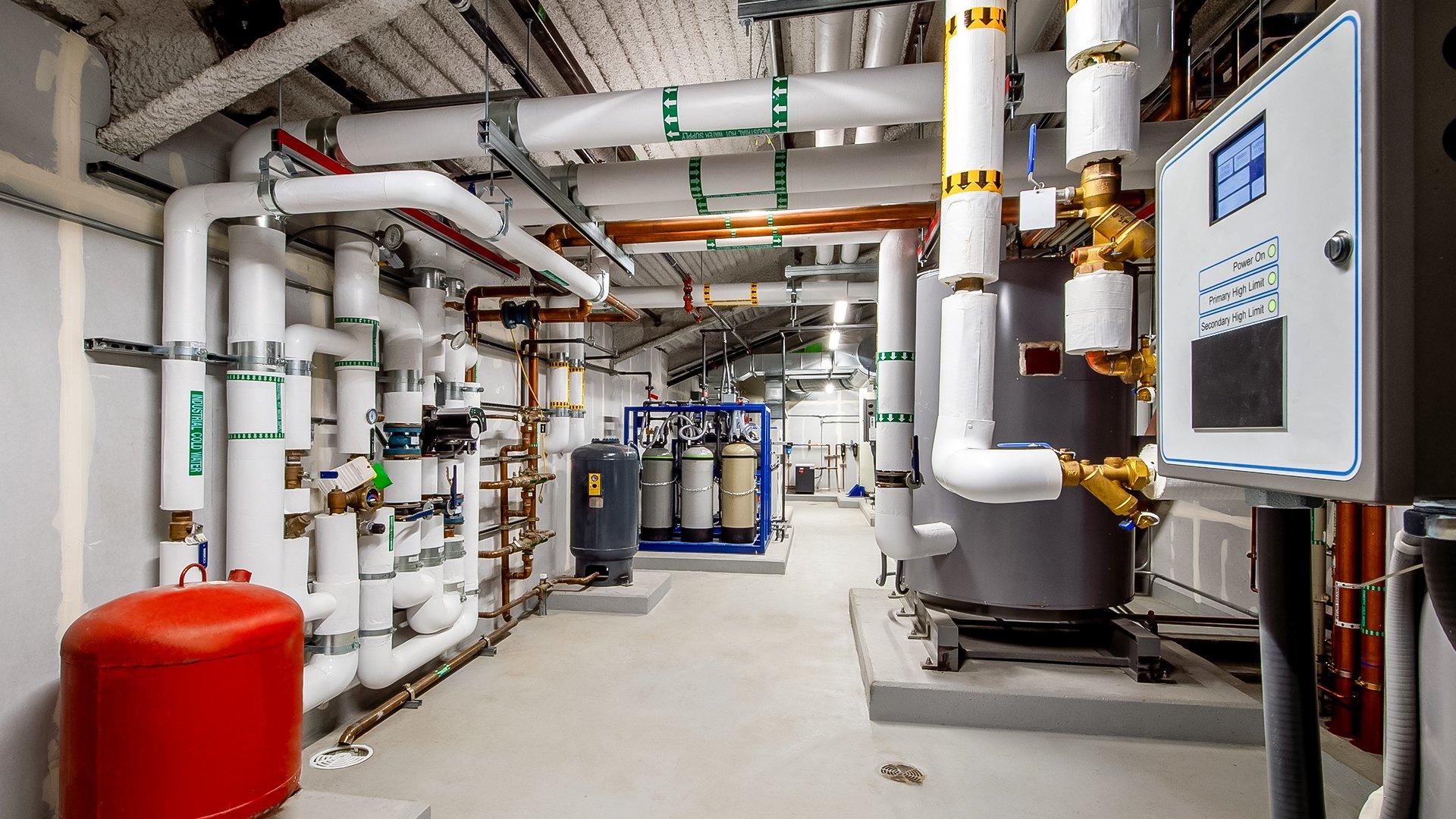 View of a mechanical room with a commercial boiler on the right.