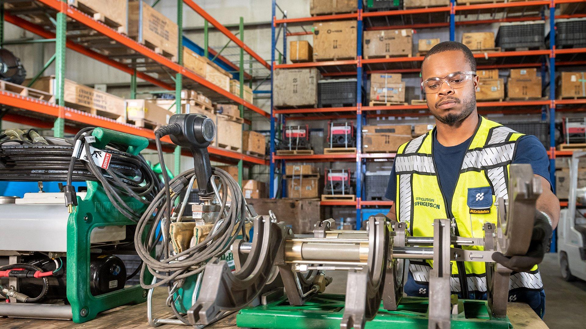 A Ferguson associate inspects fusion machine equipment in a warehouse.