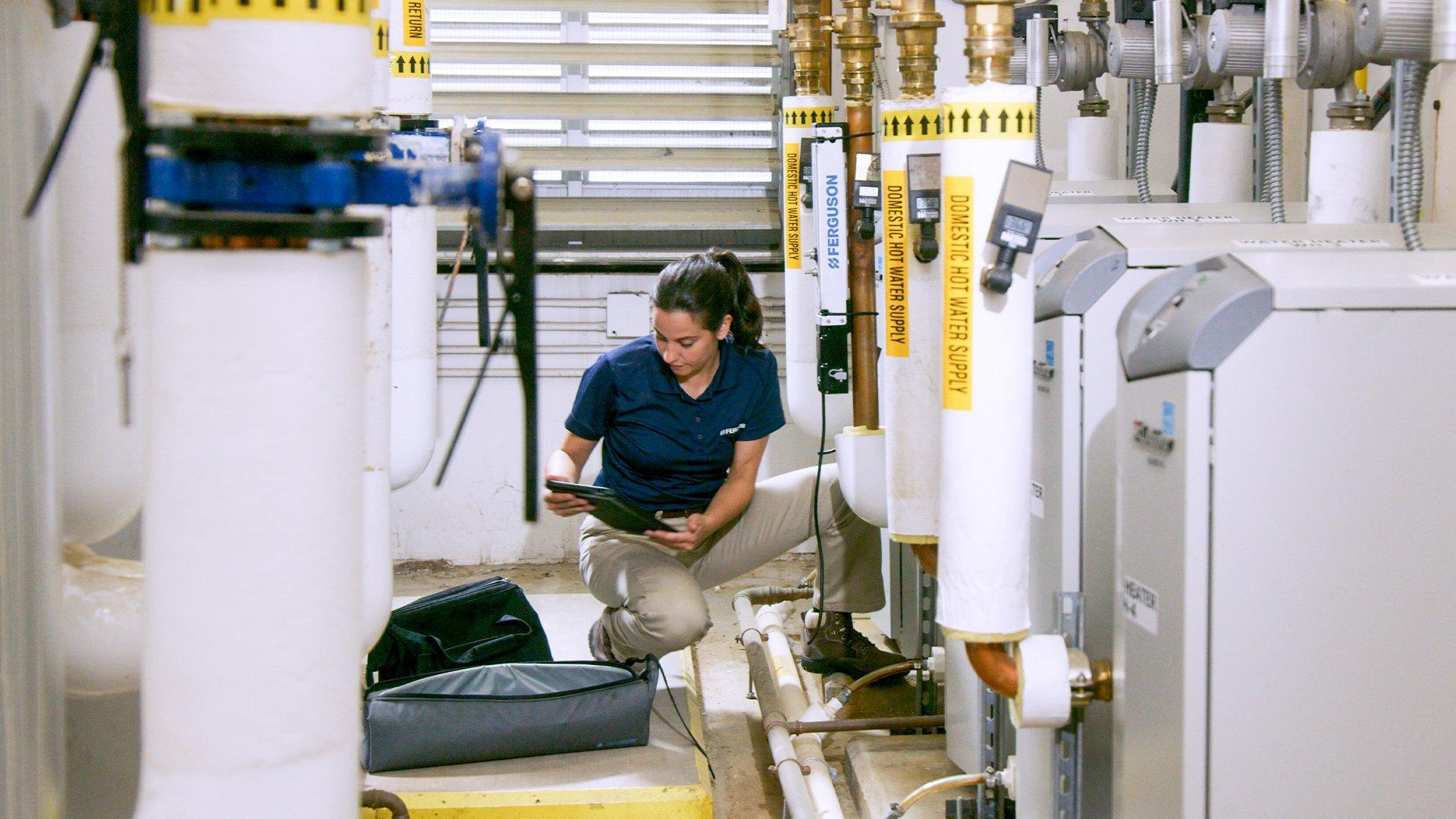 A women uses a tablet to evaluate the real-time water and energy usage data of machines in the mechanical room.