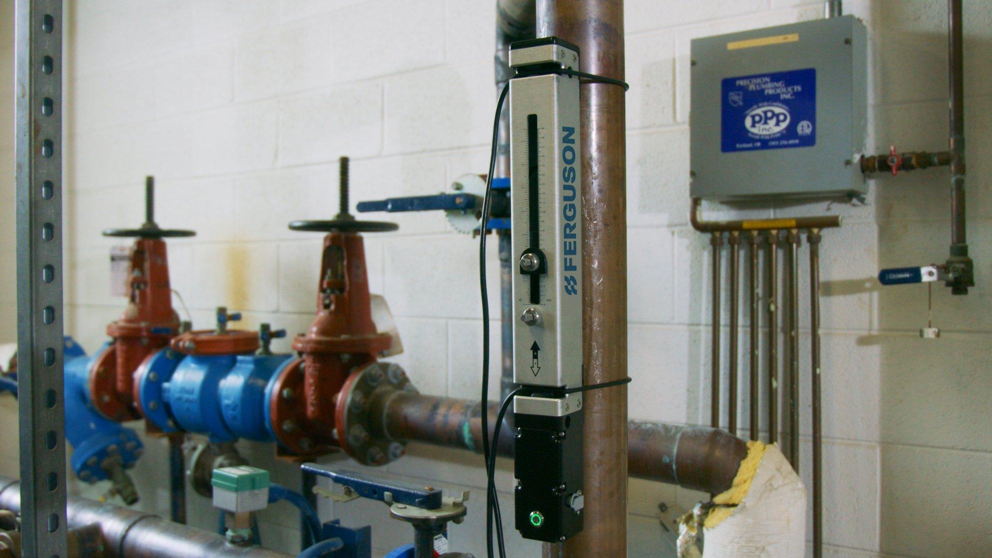 A Ferguson water line flow meter is attached to a brown pipe.