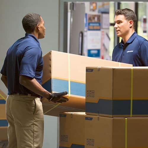 Two Ferguson associates lift a box at a distribution center.