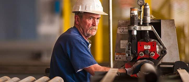 A Ferguson associate steadies a pipe on a machine.