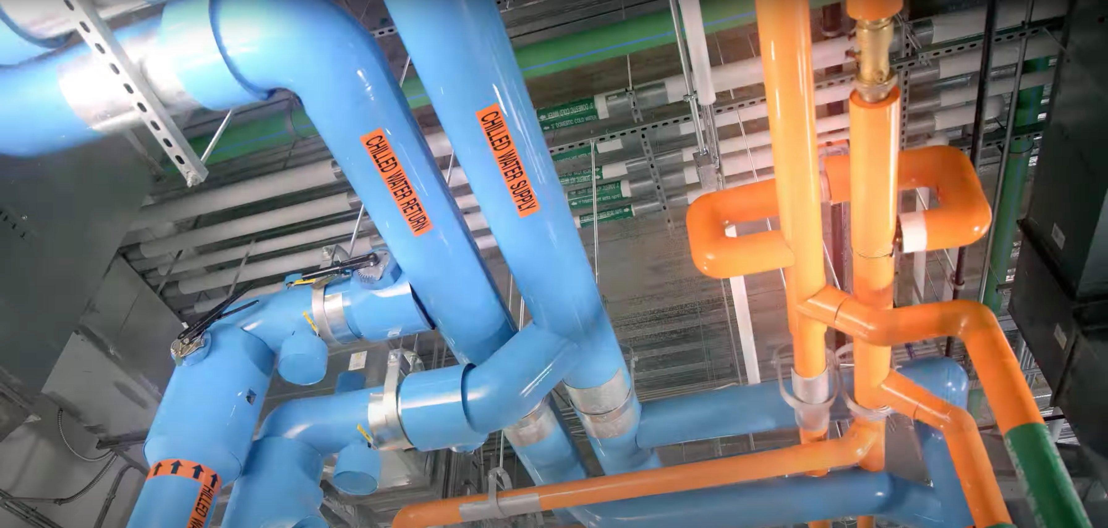 Blue and orange pipes on the ceiling in an industrial building.