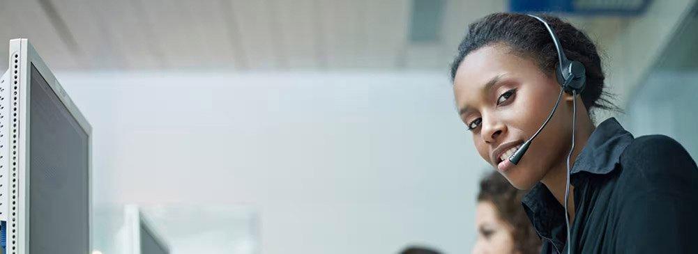 An associate wearing a headset in a call center looks at the camera.