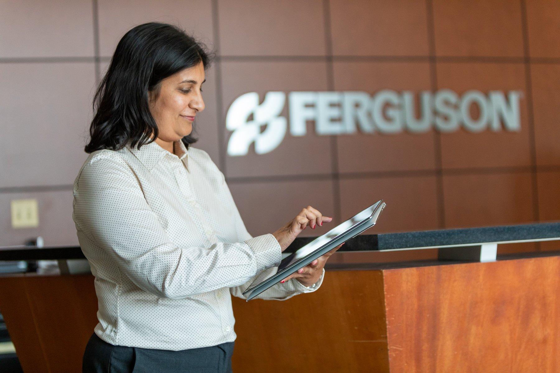 A Ferguson associate types on a tablet in front of a counter.