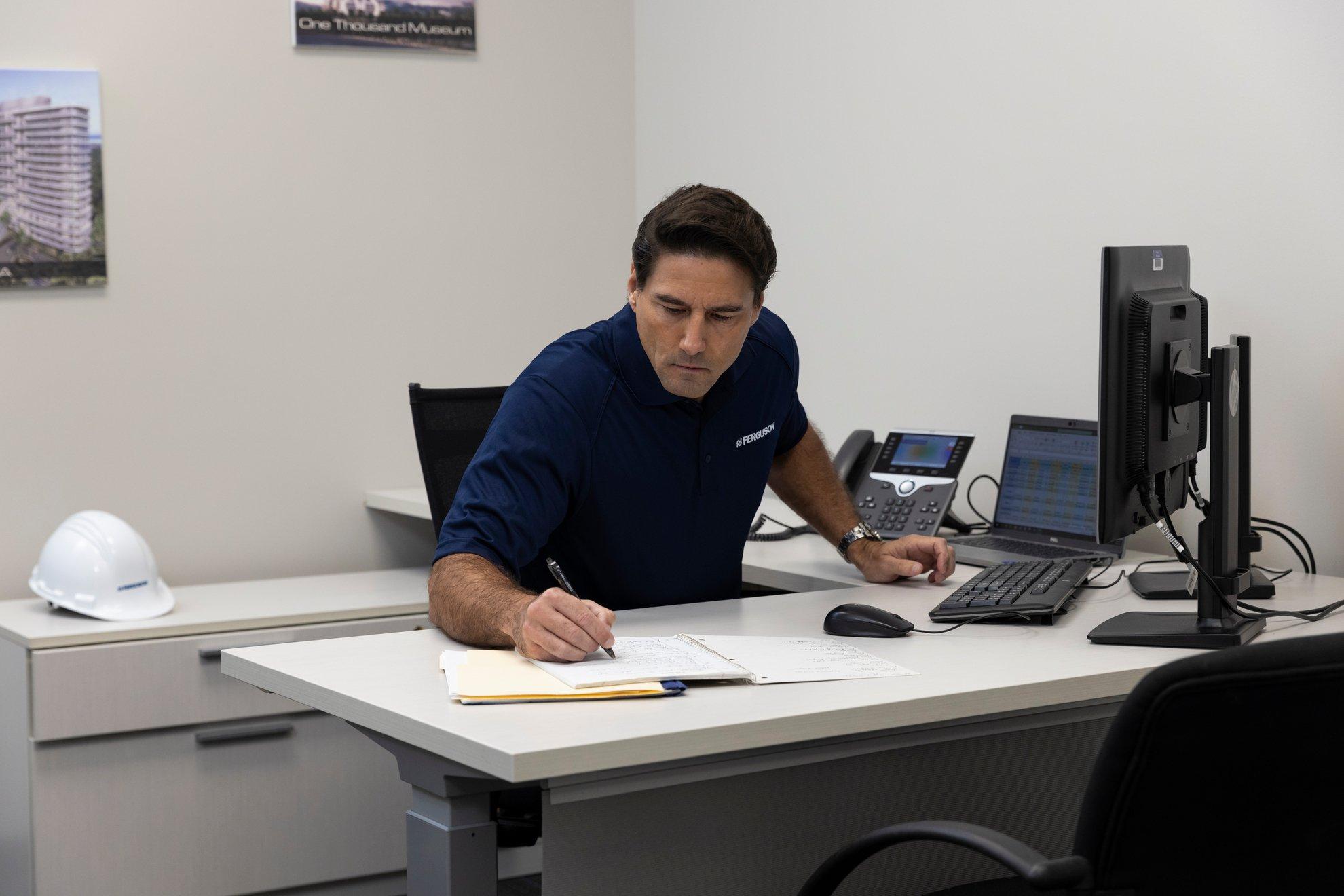 A Ferguson associate writes in a notebook at his desk.