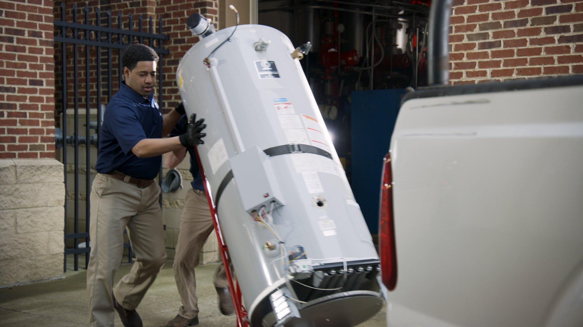 Two Ferguson associates unload a commercial water heater from a pickup truck.