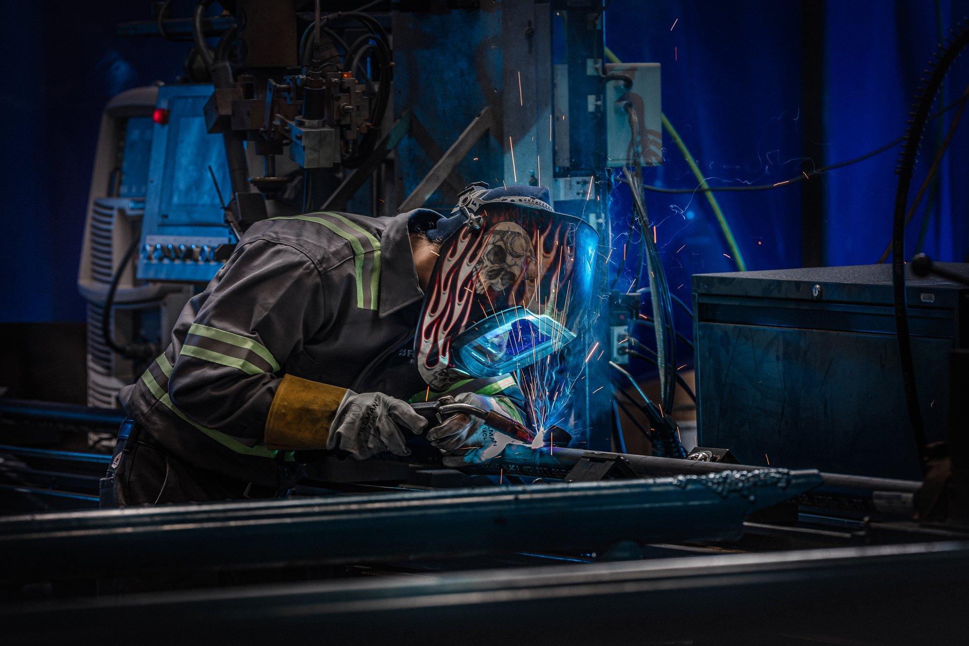 A Ferguson associate in full PPE cuts pipe on a machine.