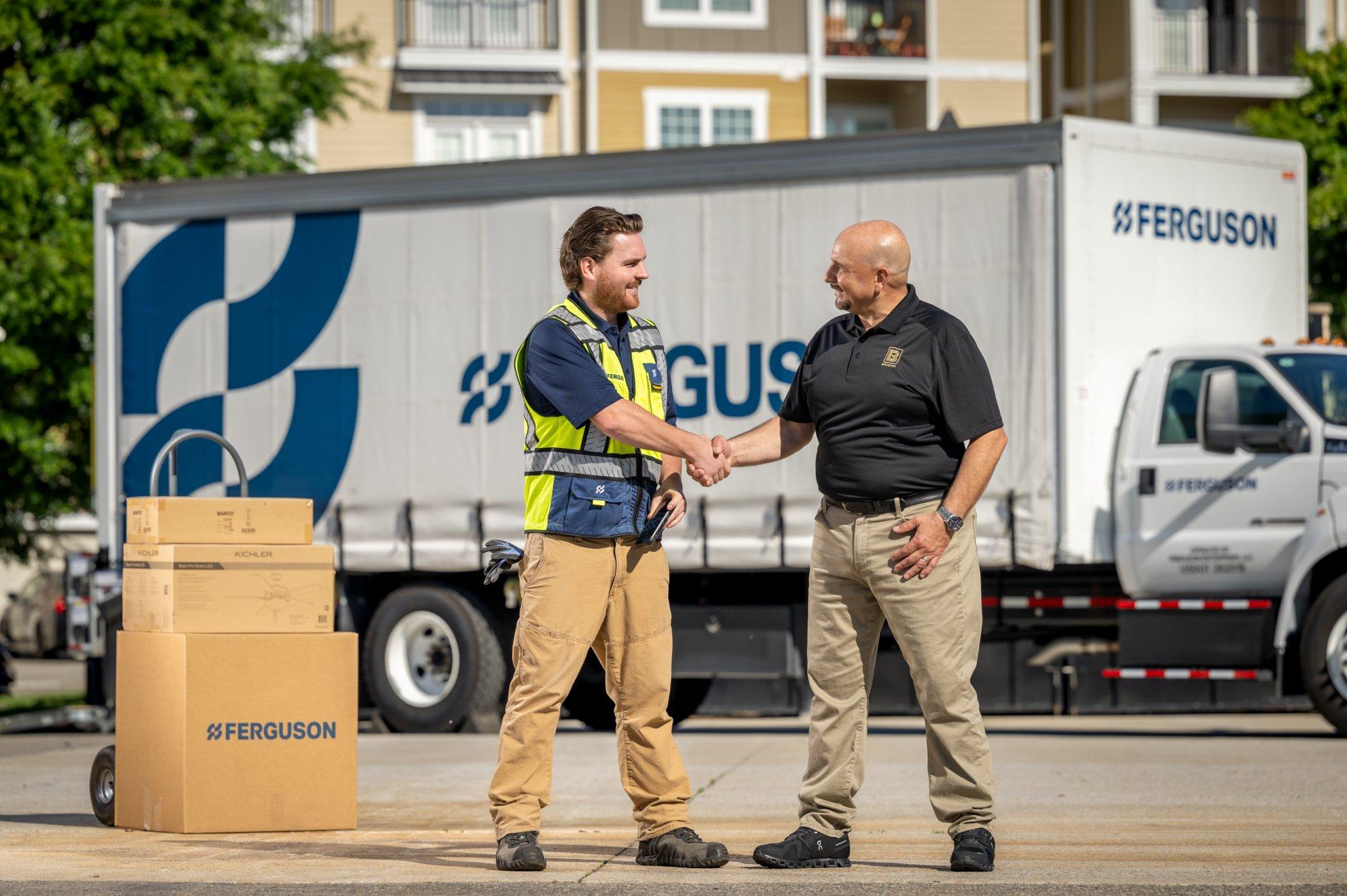 In front of a Ferguson delivery truck, an associate shakes hands with a customer.