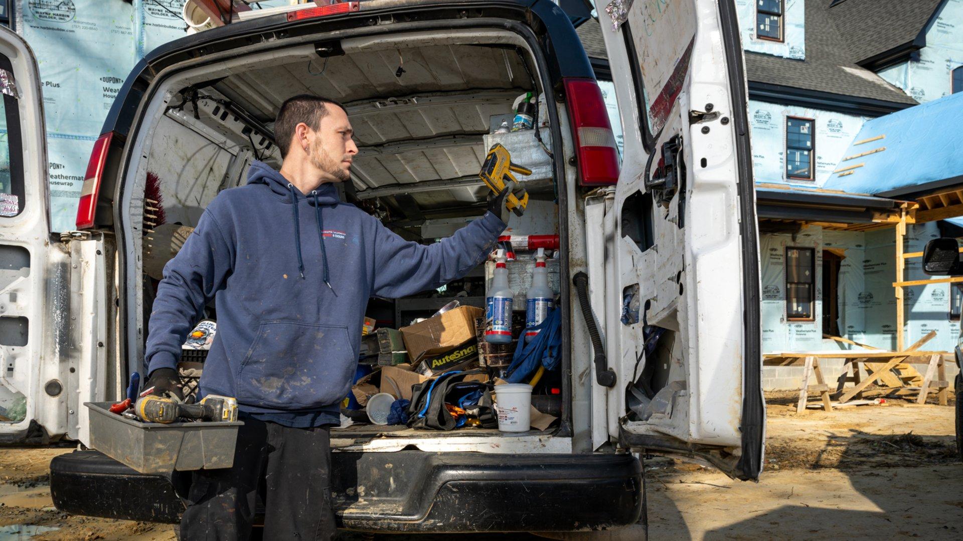 A contractor takes tools out of his work van on a residential new construction site.