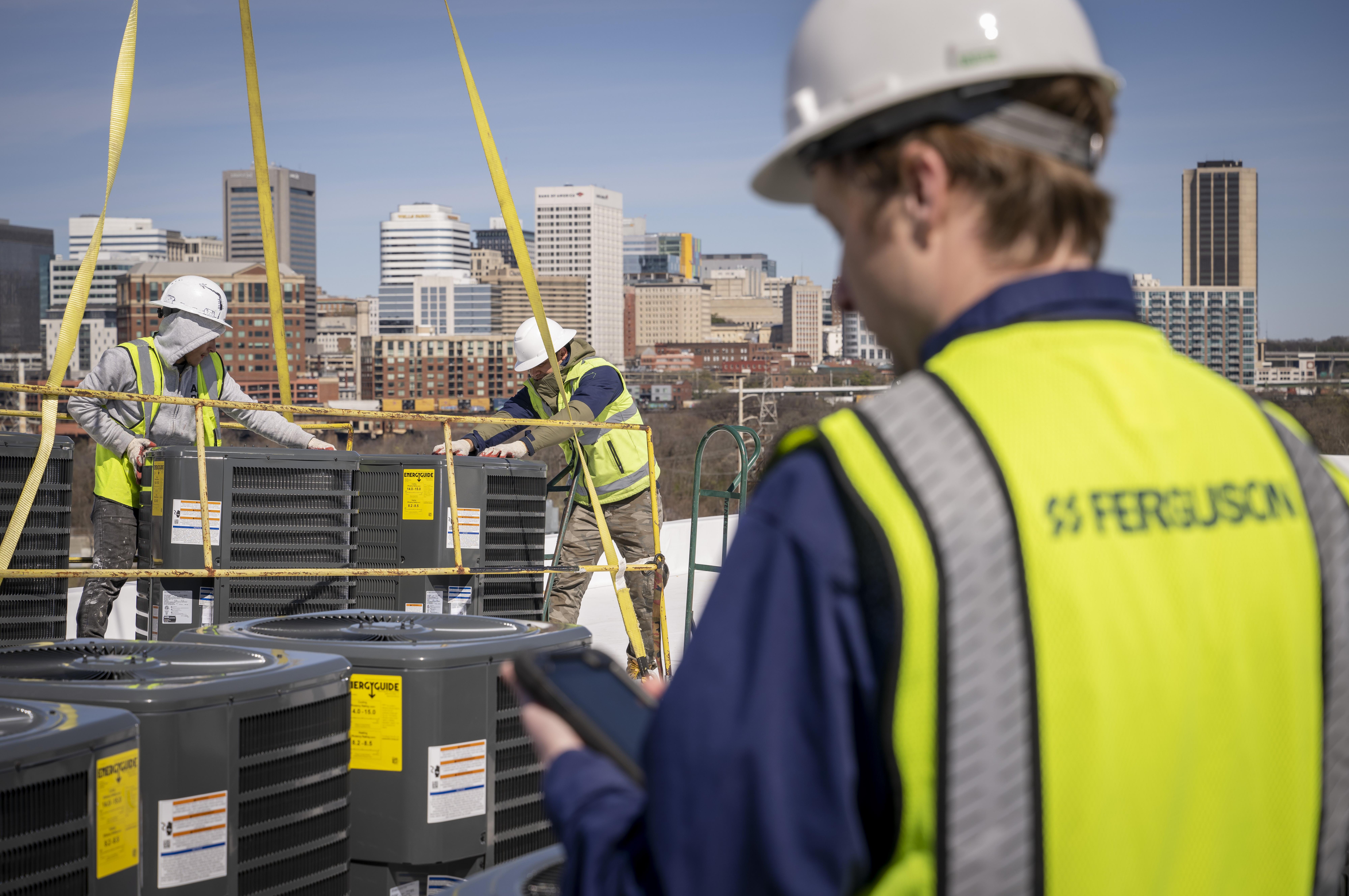 Ferguson associates install air conditioners on a rooftop.