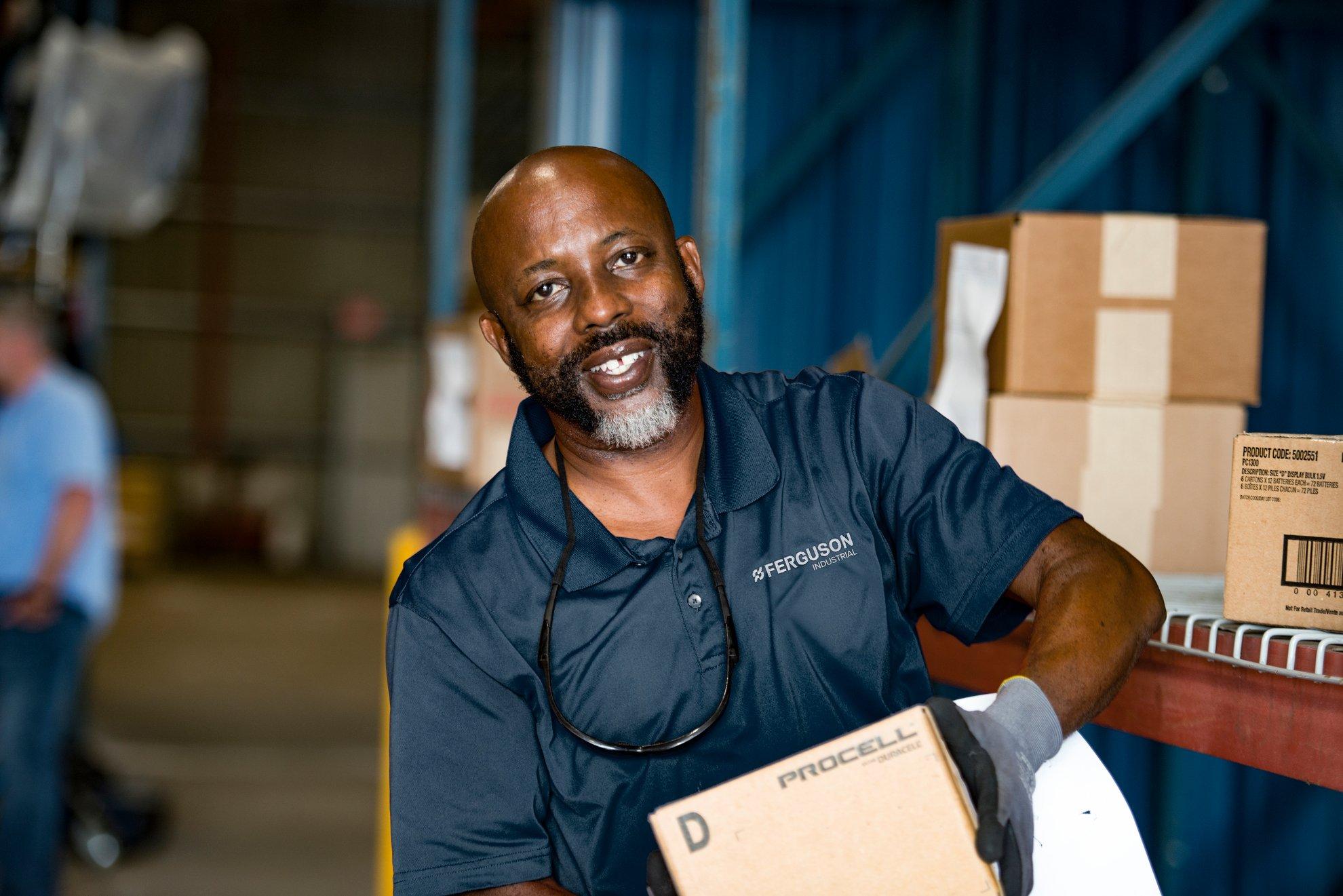 A Ferguson associate carries a box of batteries in a warehouse location.