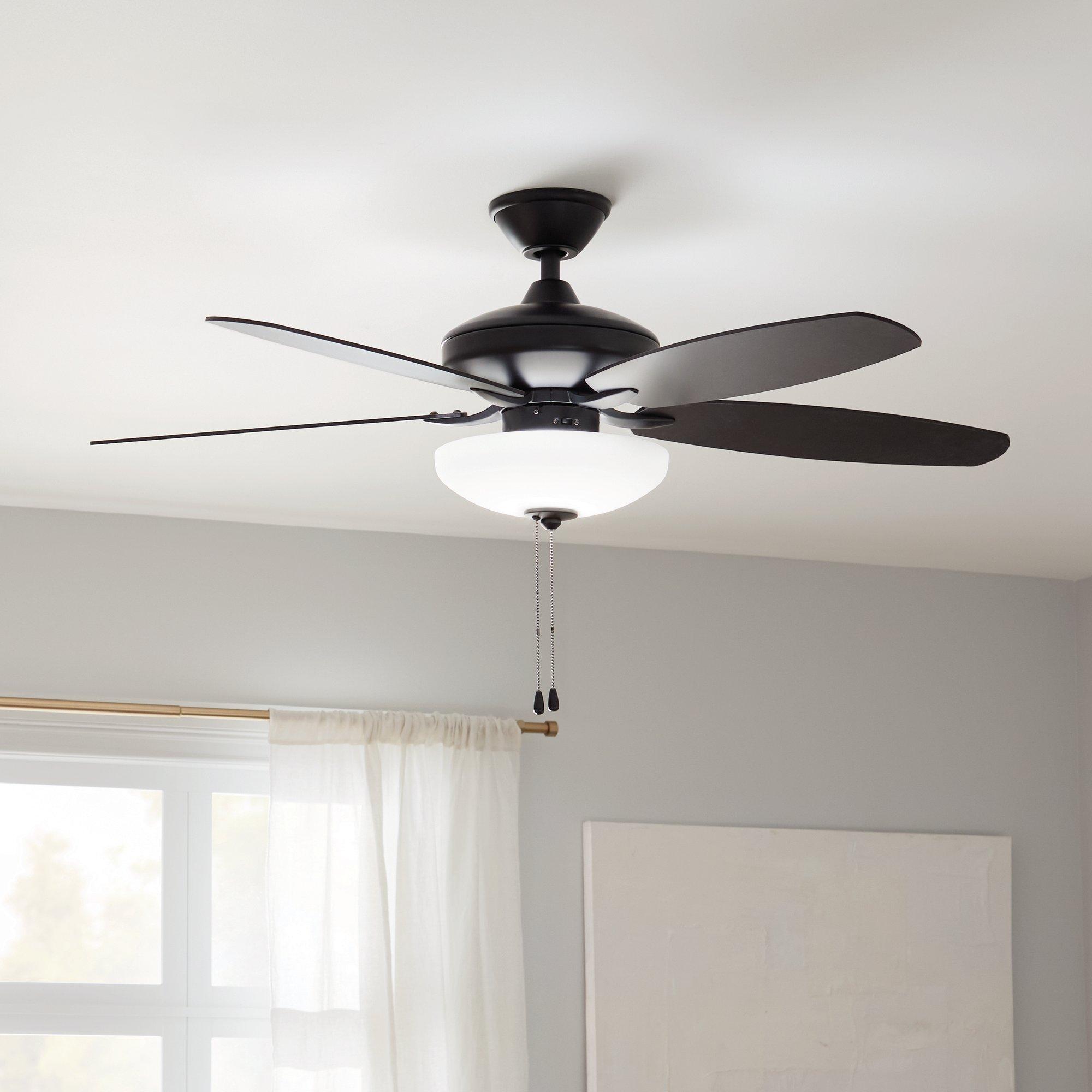 A residential ceiling fan with an LED light bowl hangs in a living room.