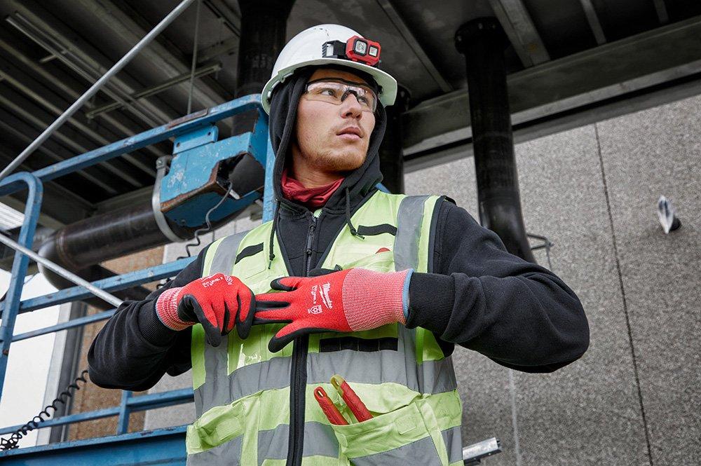 A worker at a jobsite pulls off his cut-resistant and weather-dipped safety gloves.