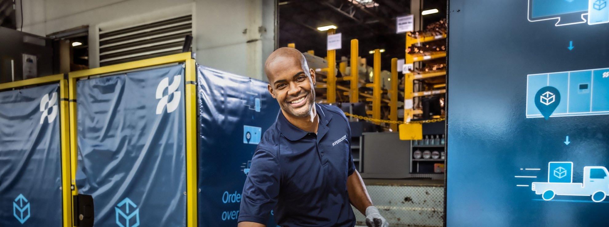 A Ferguson associate smiles in front of a Pro Pick-Up location.