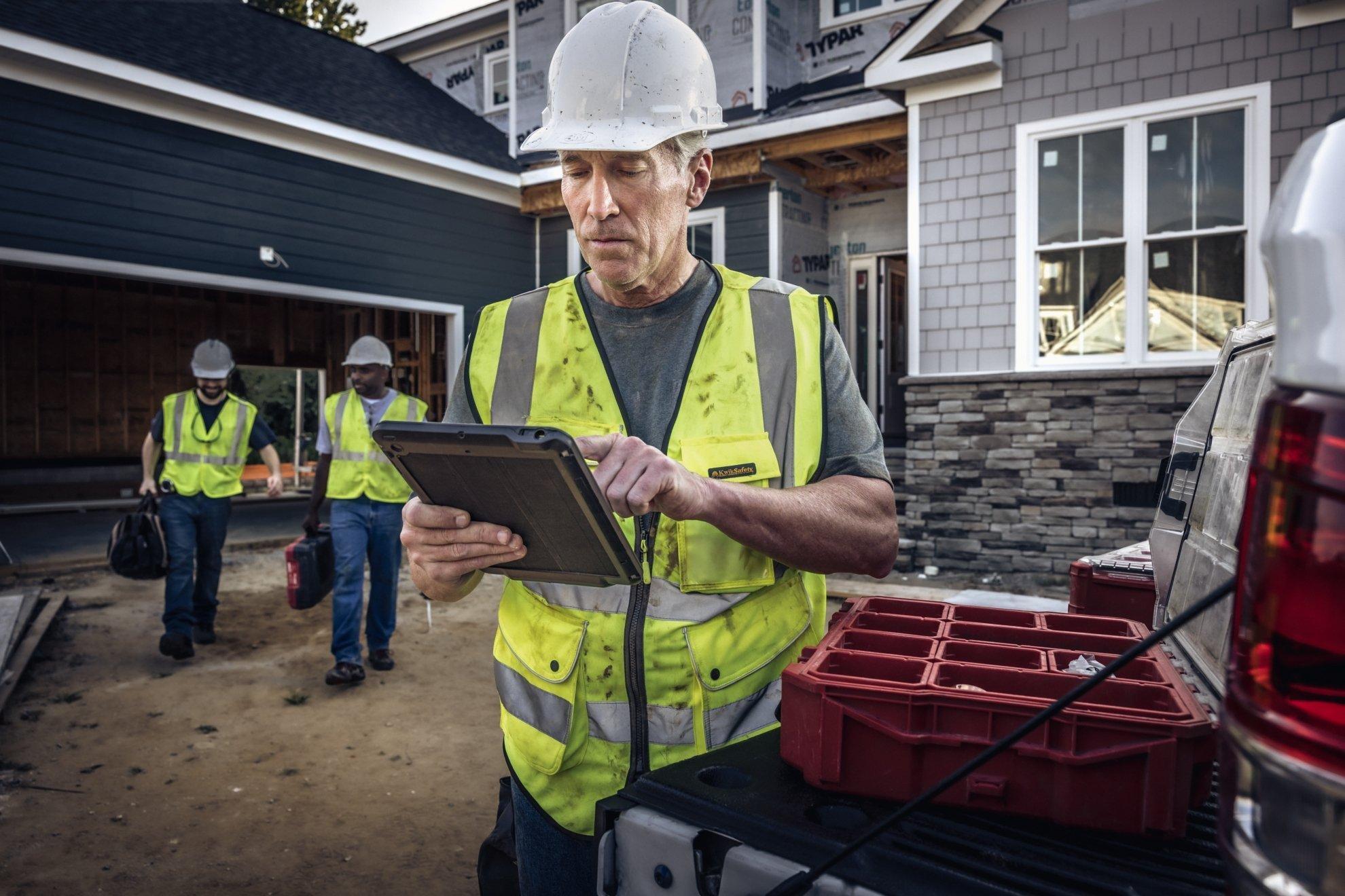 A contractor on a residential new build site scrolls through his tablet.