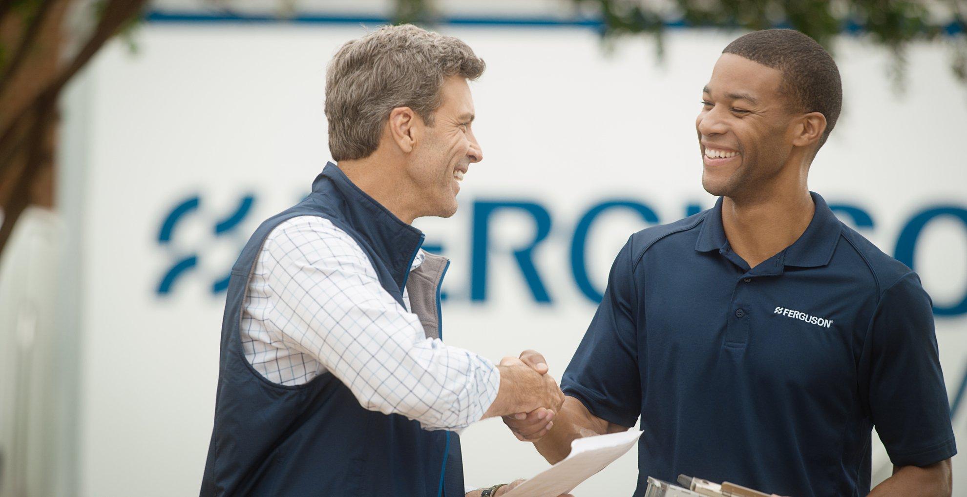 A Ferguson associate and a customer smile and shake hands in front of a delivery truck.