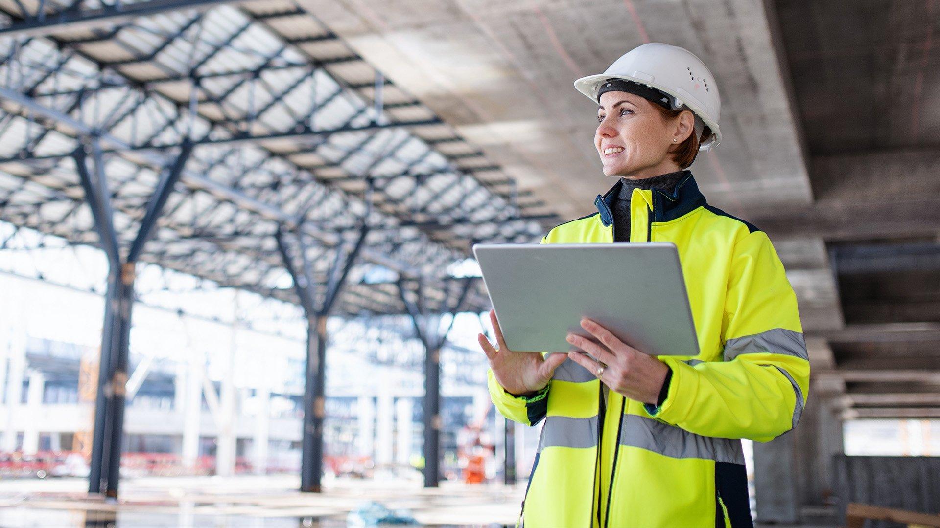 A woman engineer with tablet standing on construction site, working.