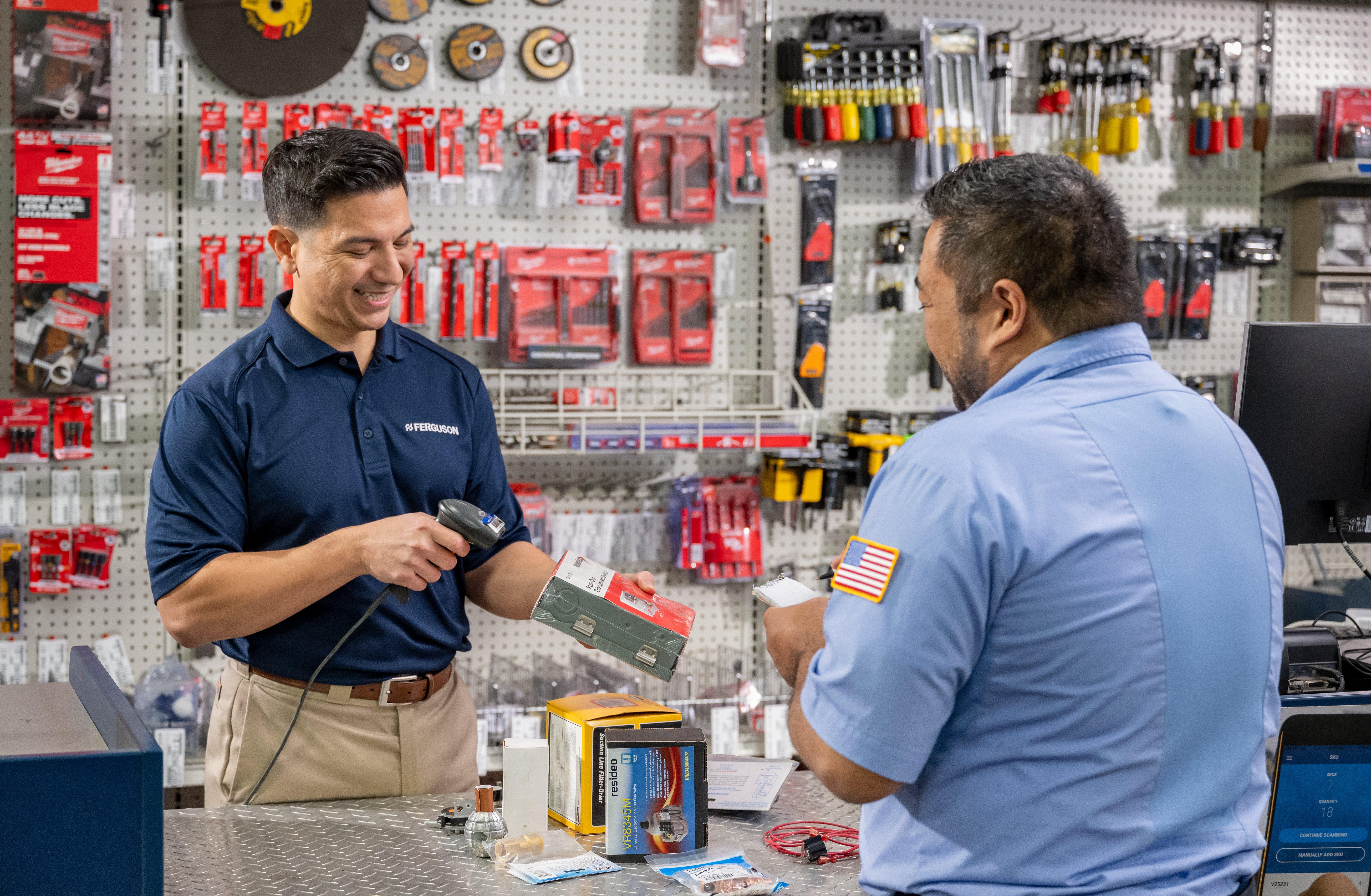 An associate discusses a product with a contractor at a Ferguson counter location.