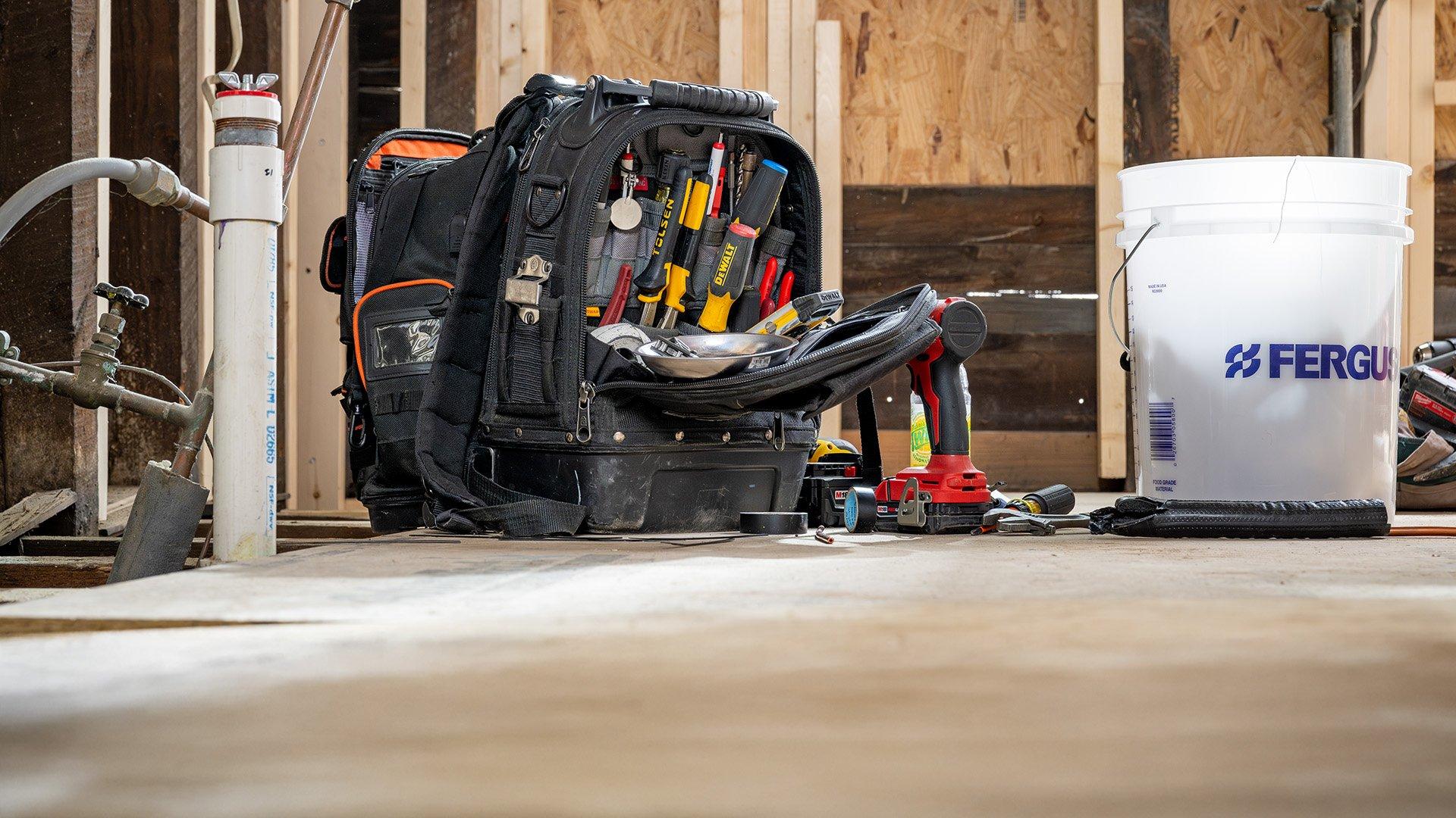 HVAC technician tool bag with tools and Ferguson bucket in residential home. 