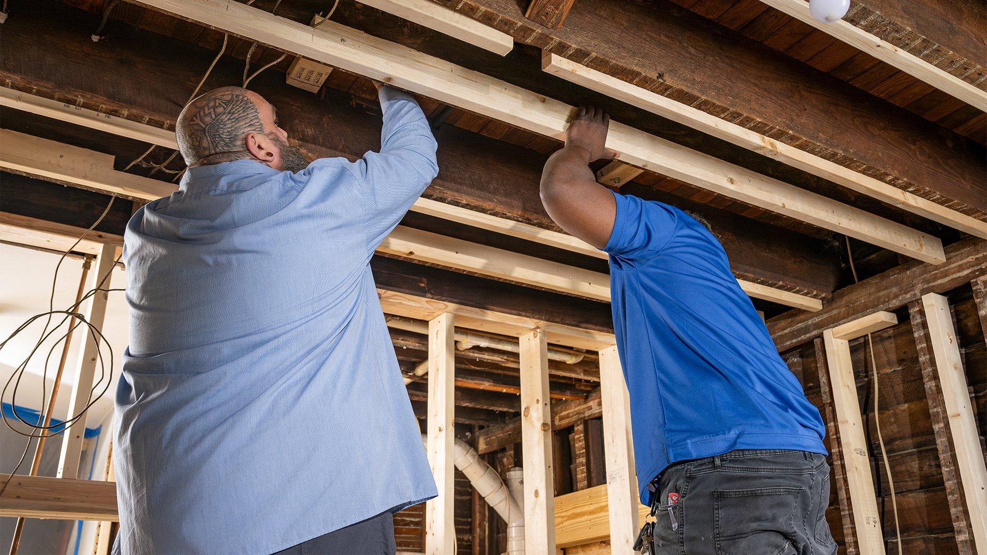 Contractors assess structure beams in residential building. 