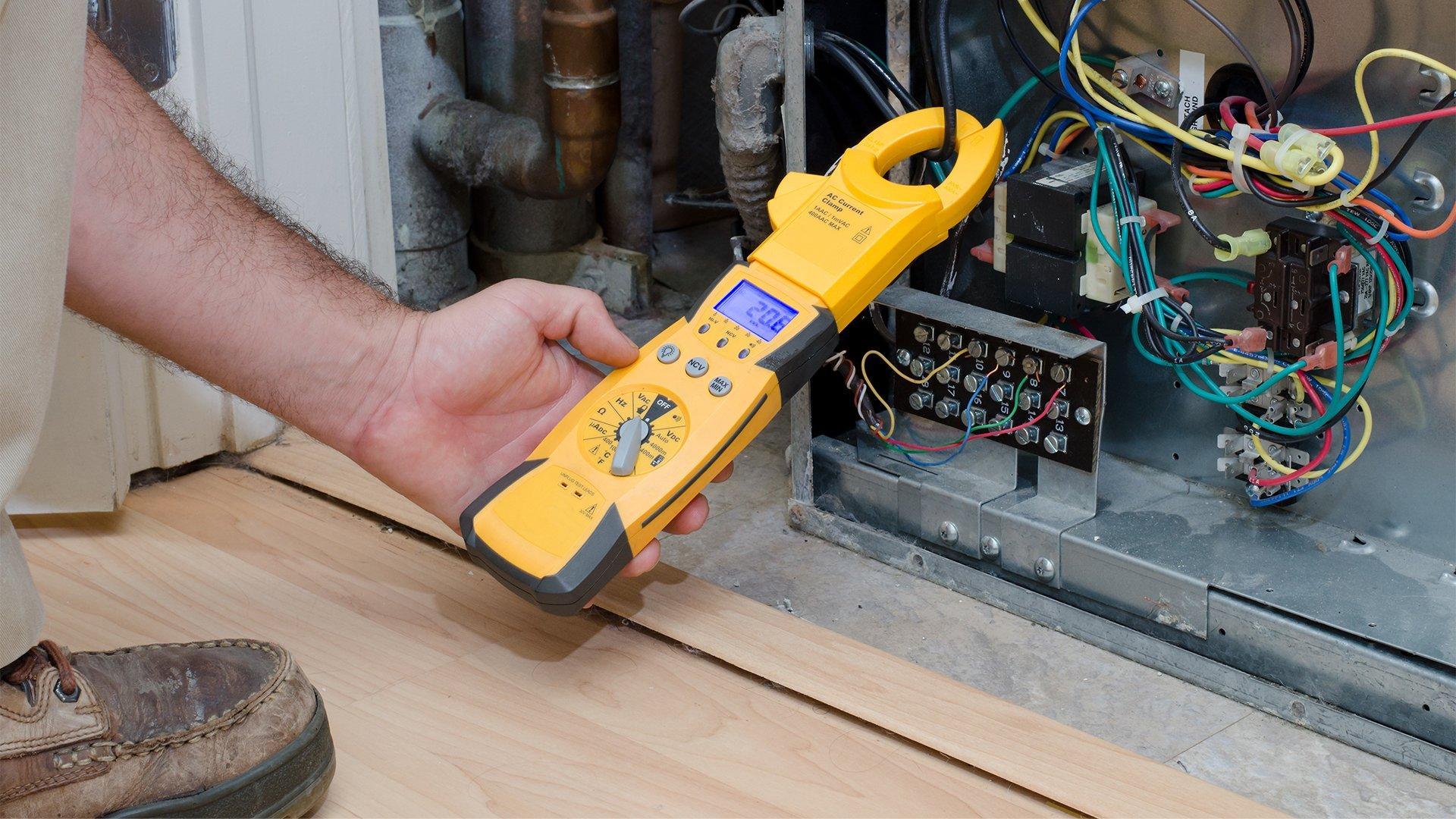 HVAC technician uses an electrical multimeter to test residential unit.