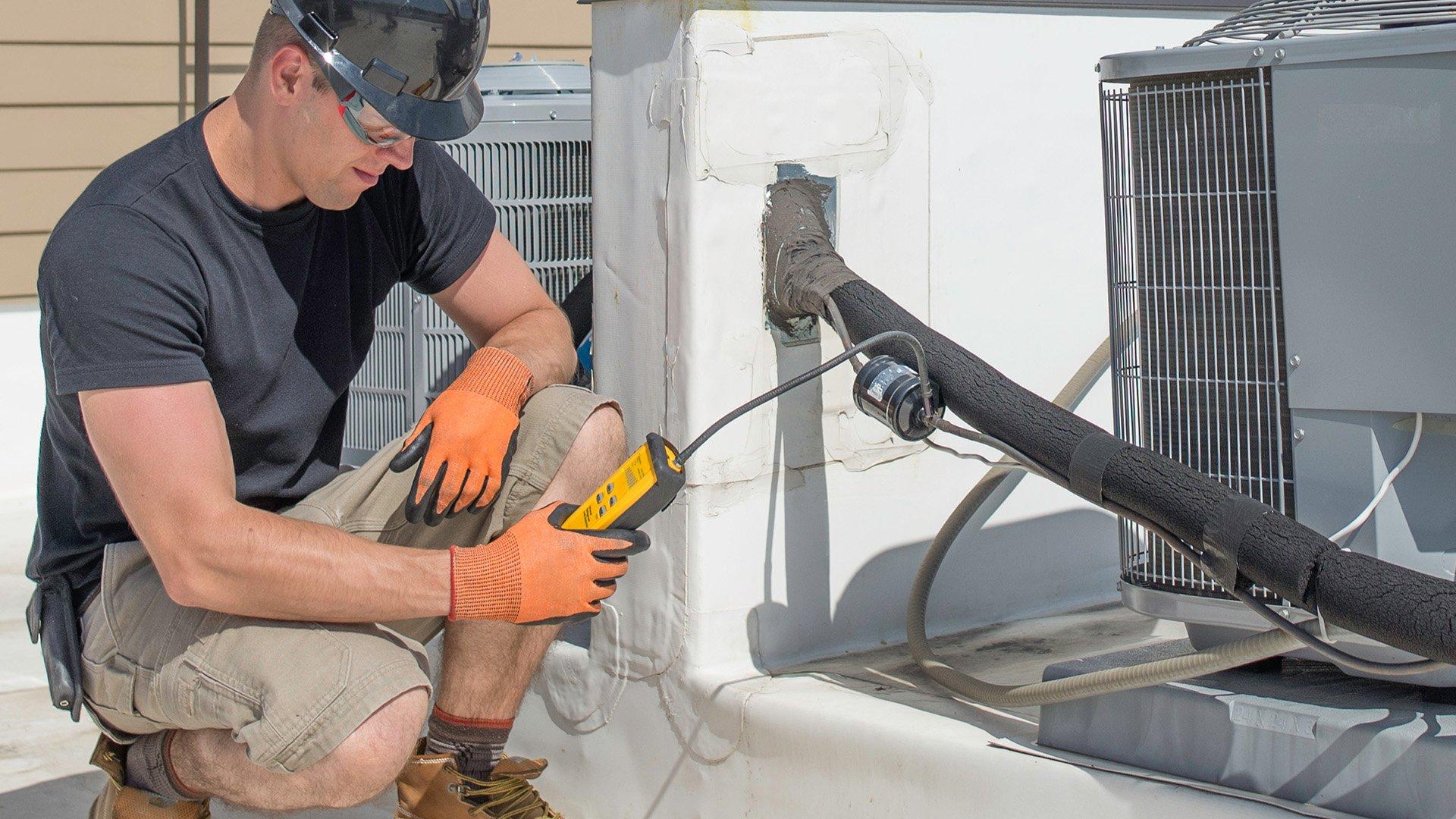 HVAC technician uses field tool on air handler on residential unit. 
