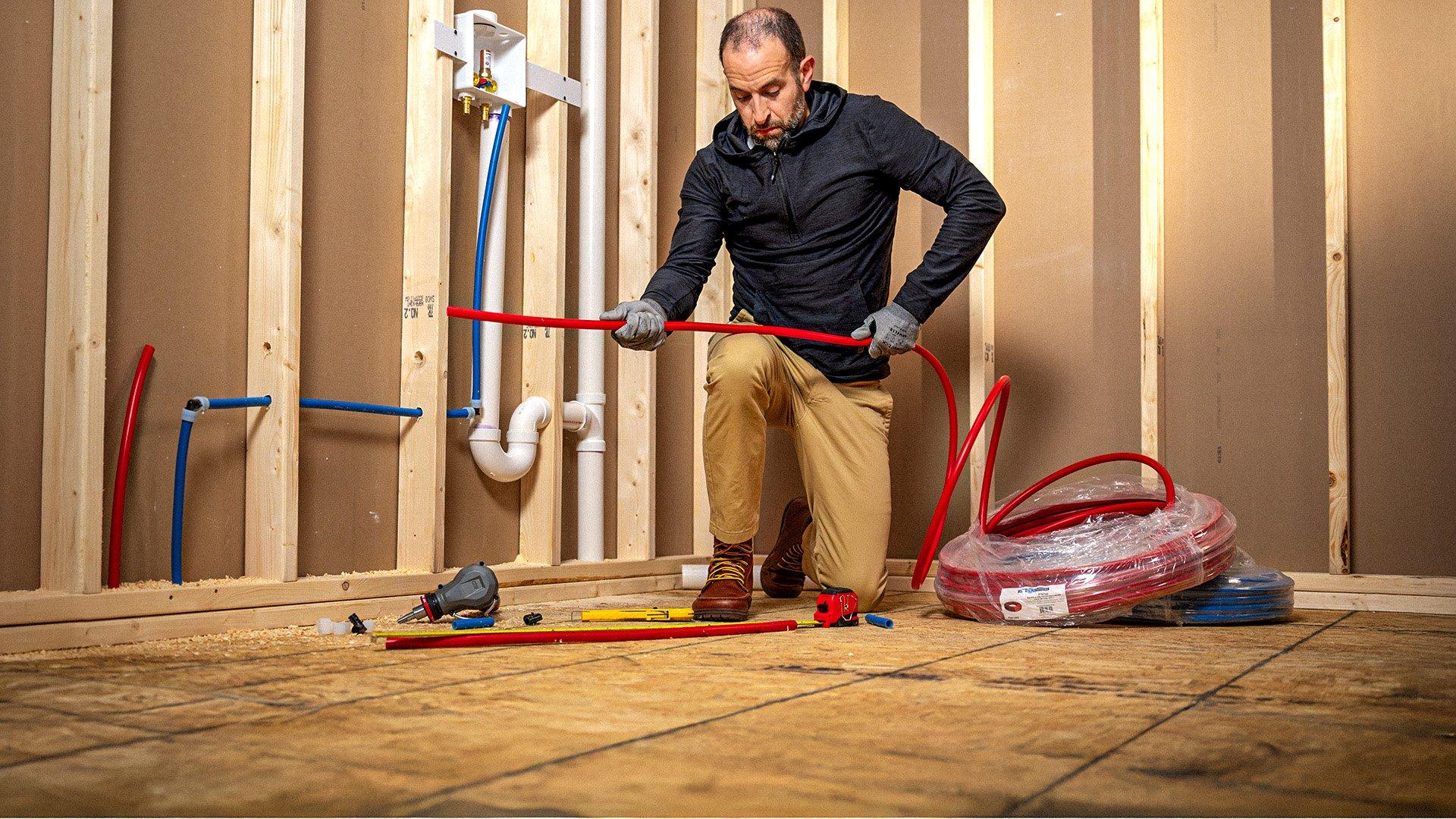 Plumber installs PEX piping into an unfinished residential home.