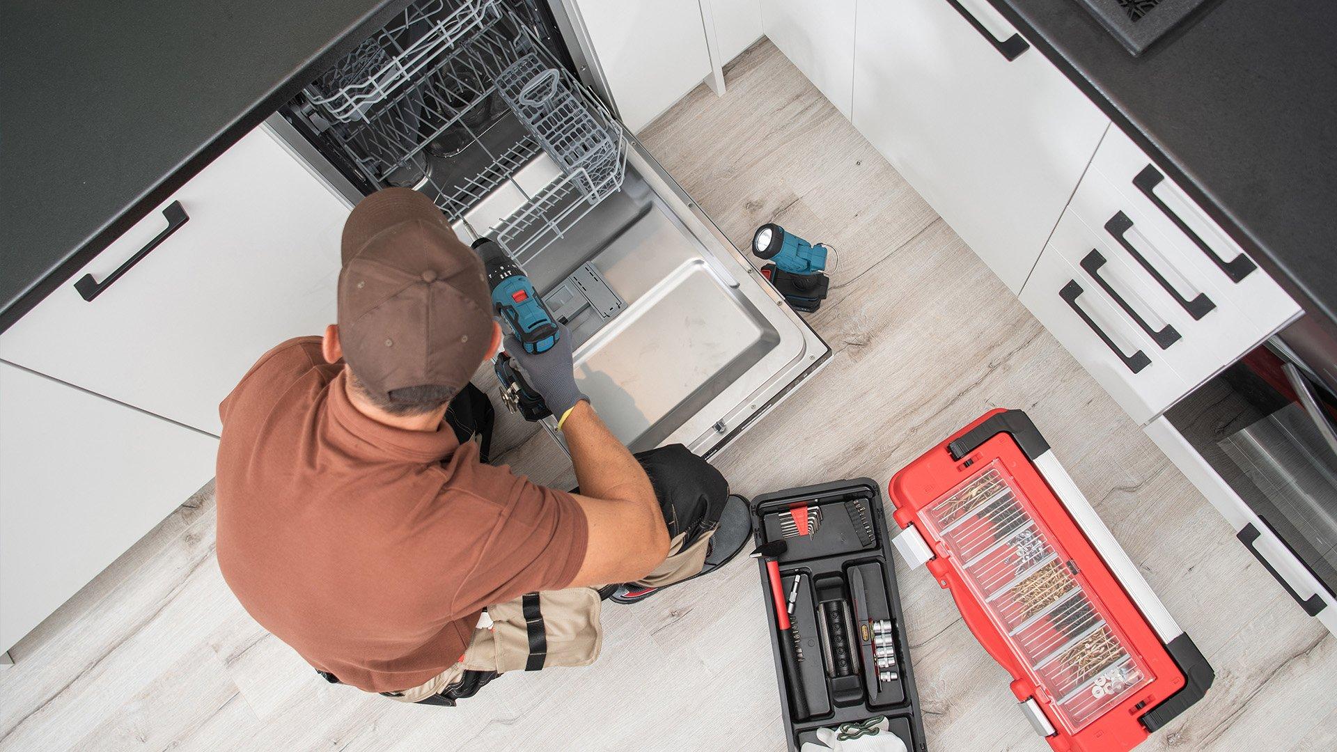 Overhead shot of plumber installing a dishwasher in residential kitchen.