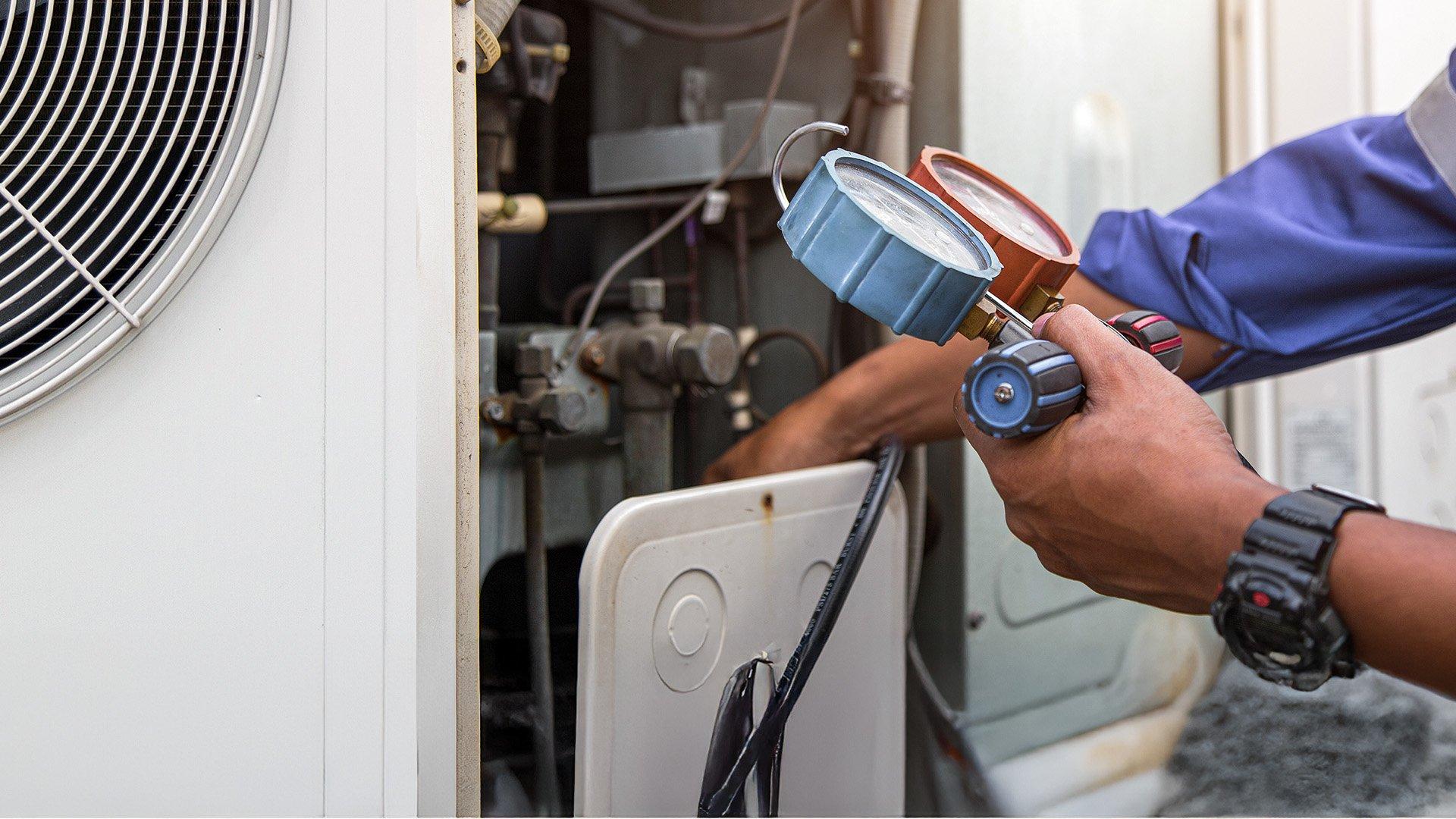HVAC Technician uses a manifold to measure HVAC pressure on outdoor unit. 
