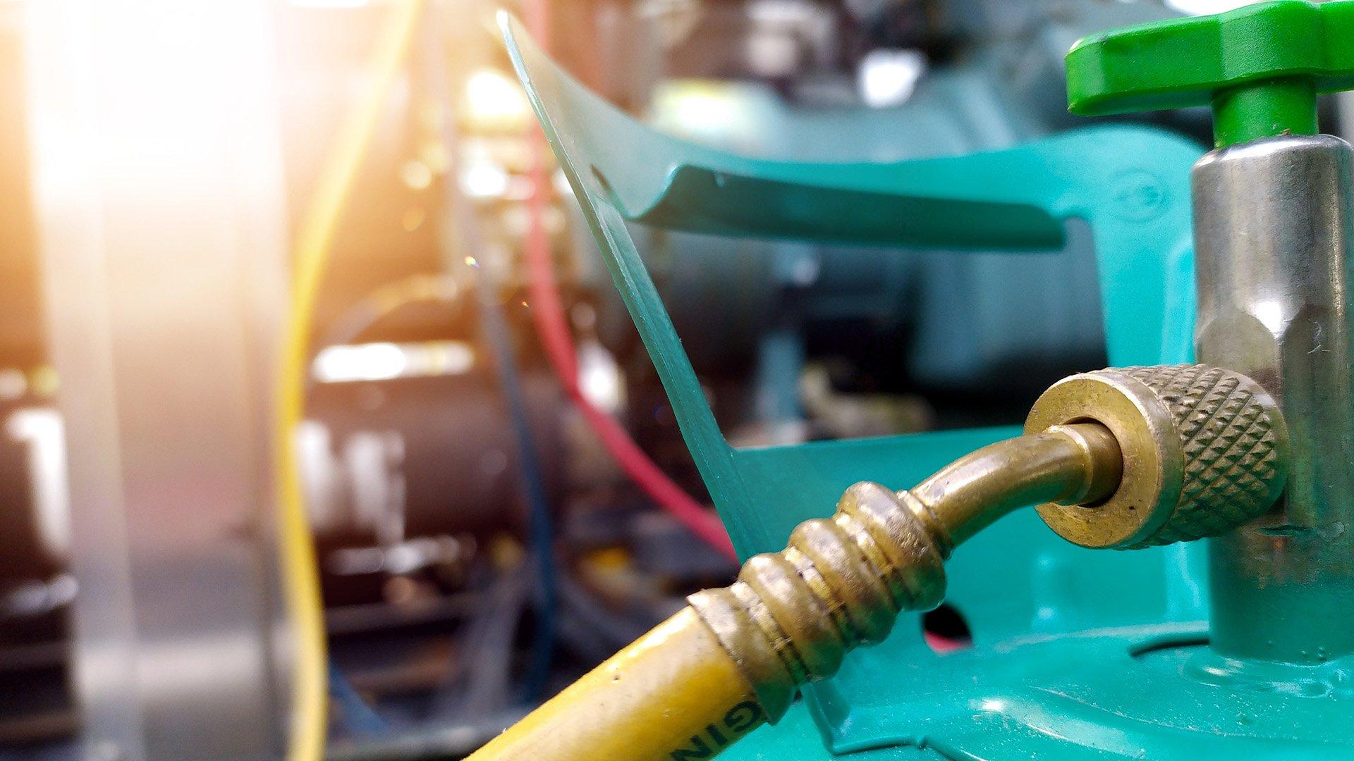 Close up imagery of yellow hose with a brass fitting connected to teal tank. 