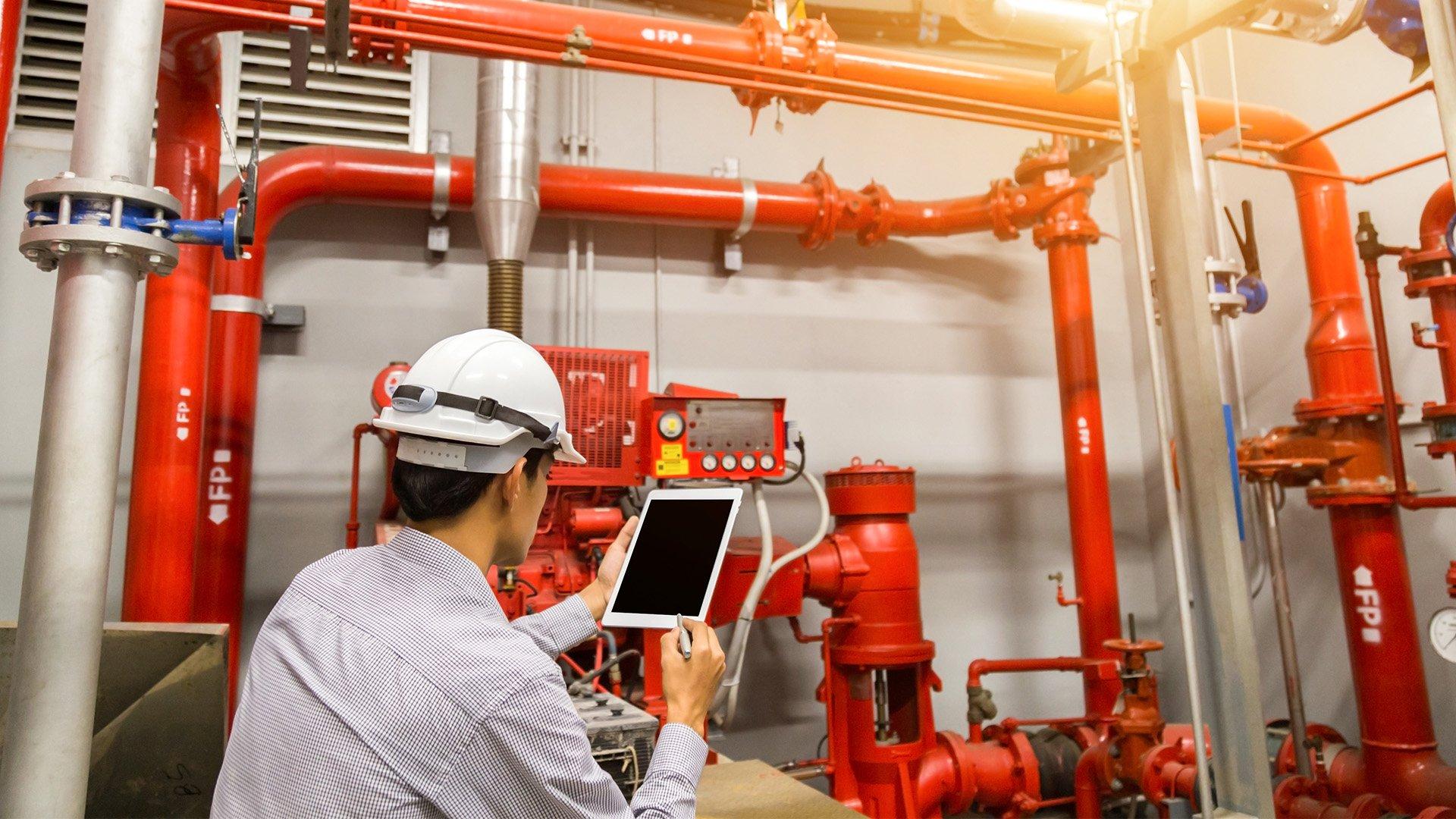 Engineer holds tablet in front of sprinkler system.