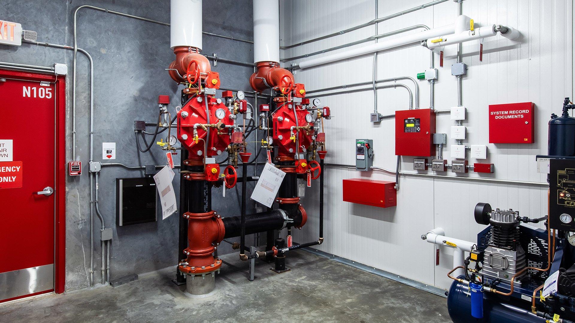 Inside of a sprinkler room showcasing pipes, valves and emergency equipment. 