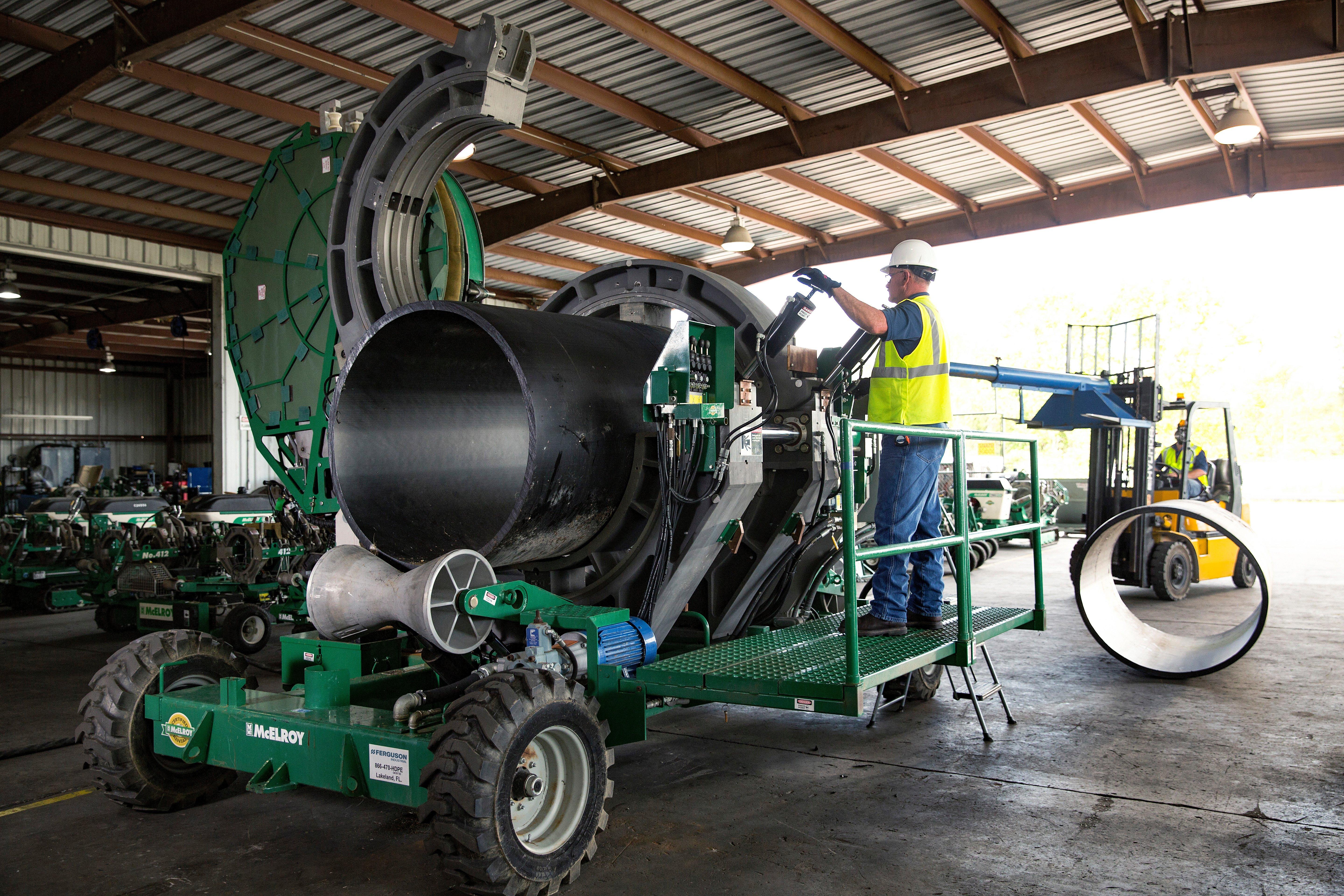 A Ferguson associate wearing protective apparel examines a pipe fusion machine on a tow bed.