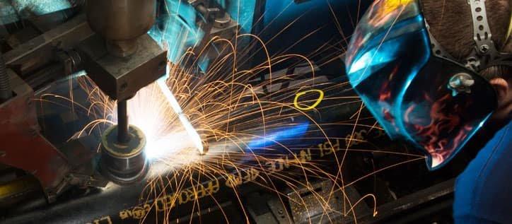 A Ferguson associate in full PPE cuts pipe on a machine.