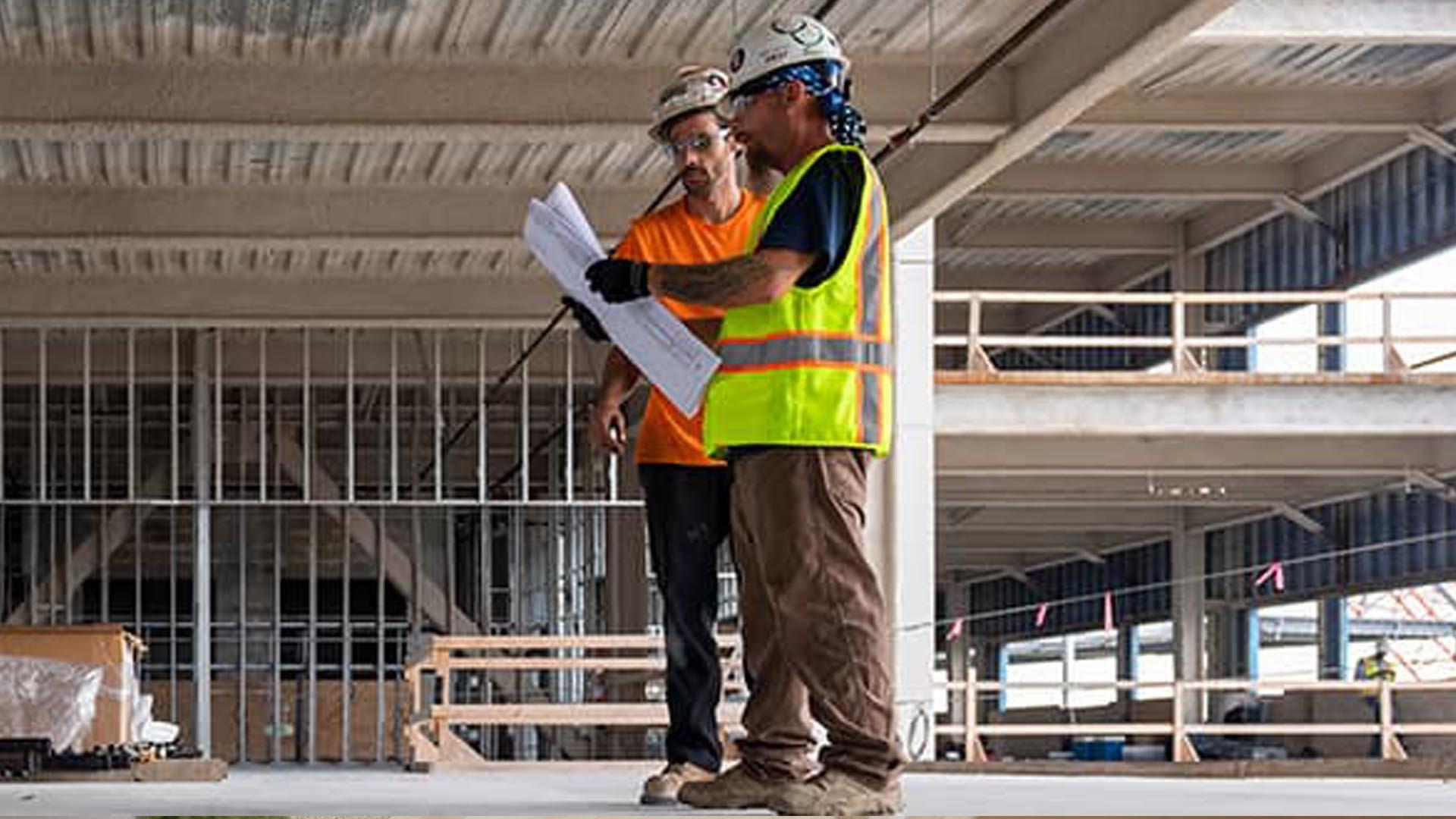 Two contractors review a design in a commercial new build.