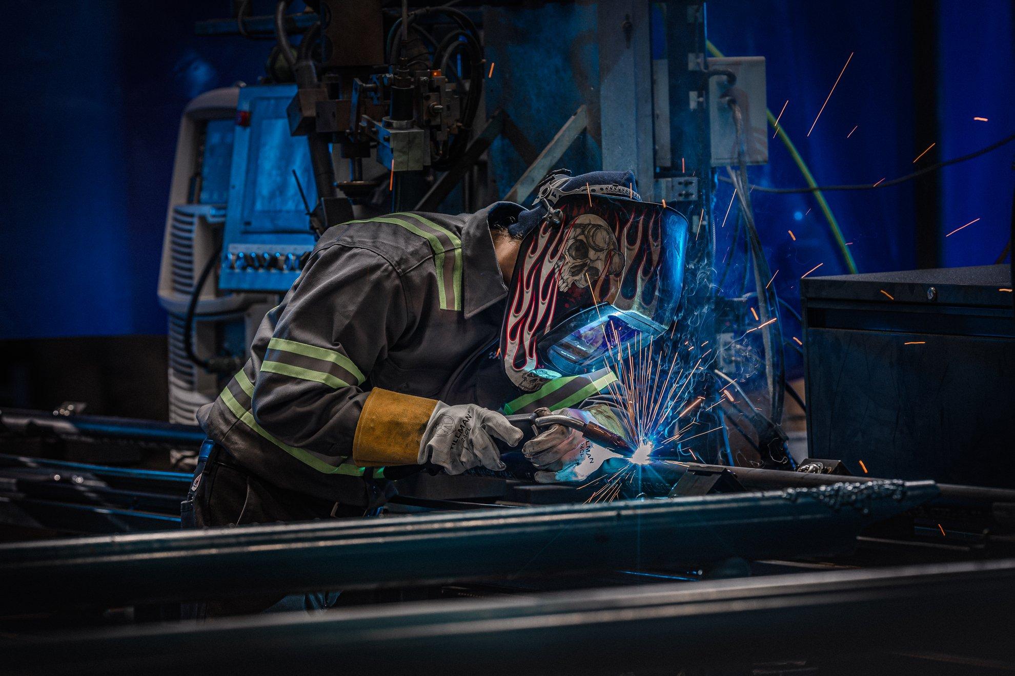 A Ferguson associate in full PPE cuts pipe on a machine.