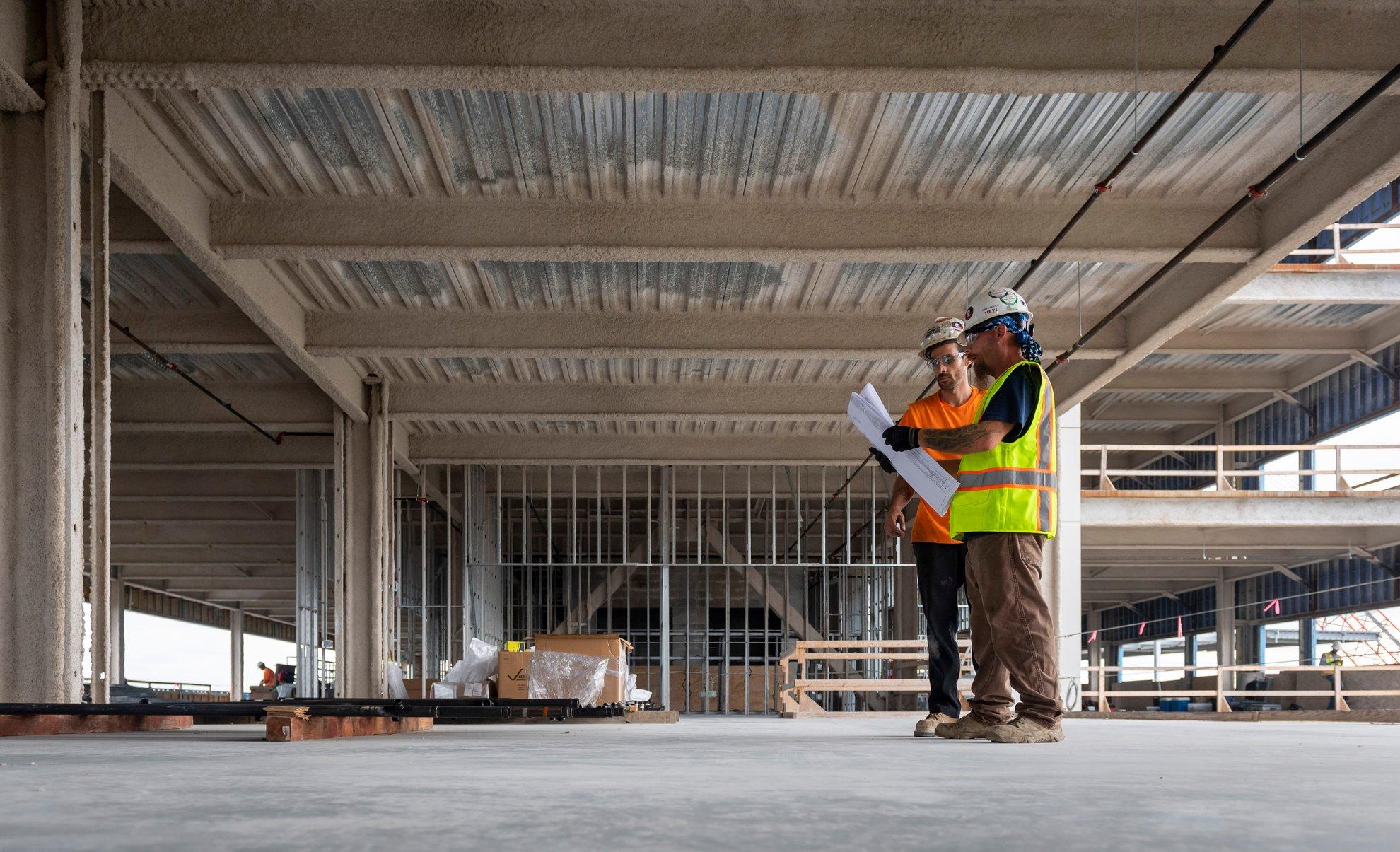 Two contractors review a design in a commercial new build.