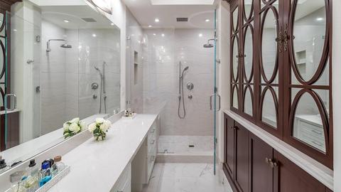 A white bathroom with walk-in shower and mirrors on the right.