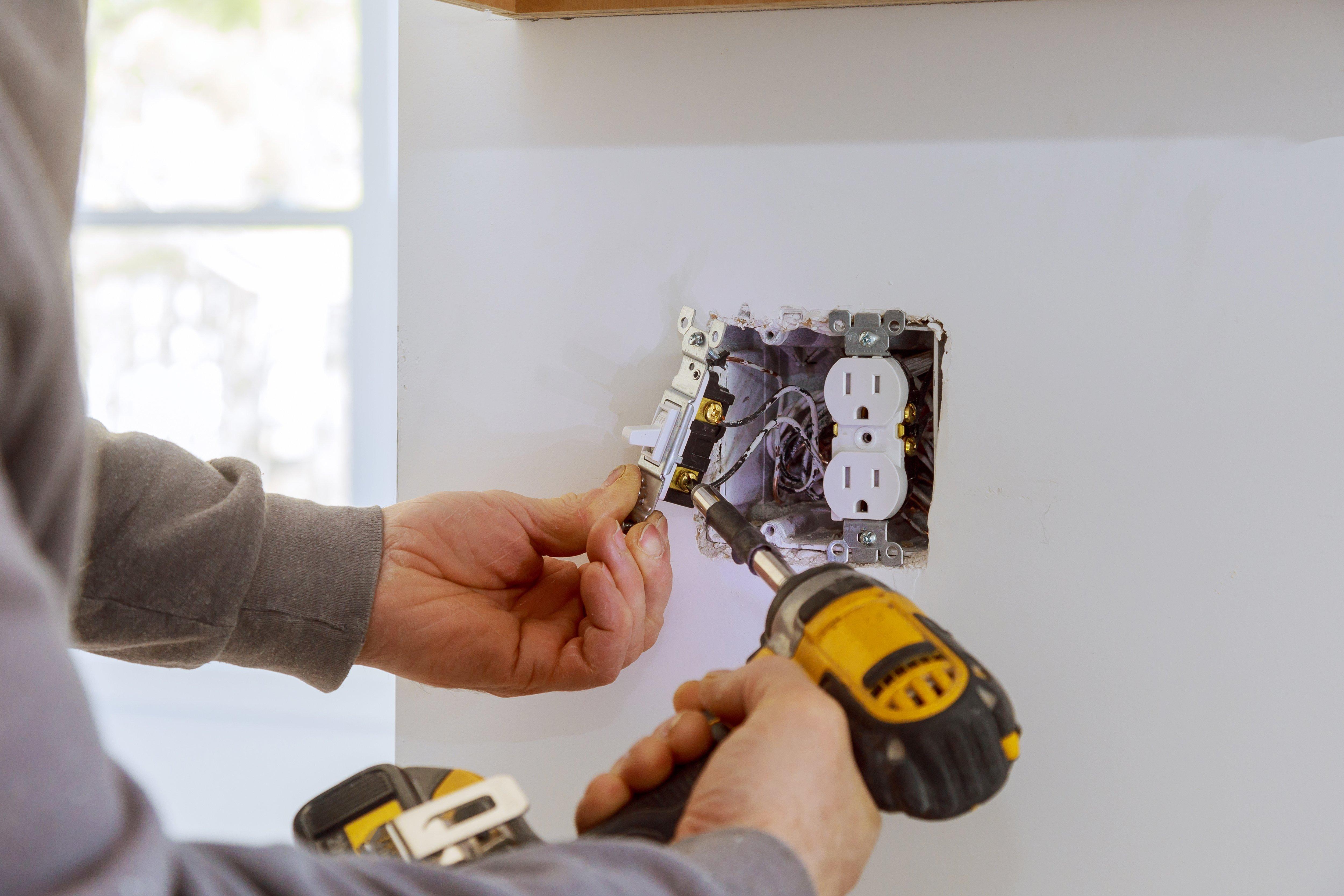 A contractor installs electrical outlets in a residential home.