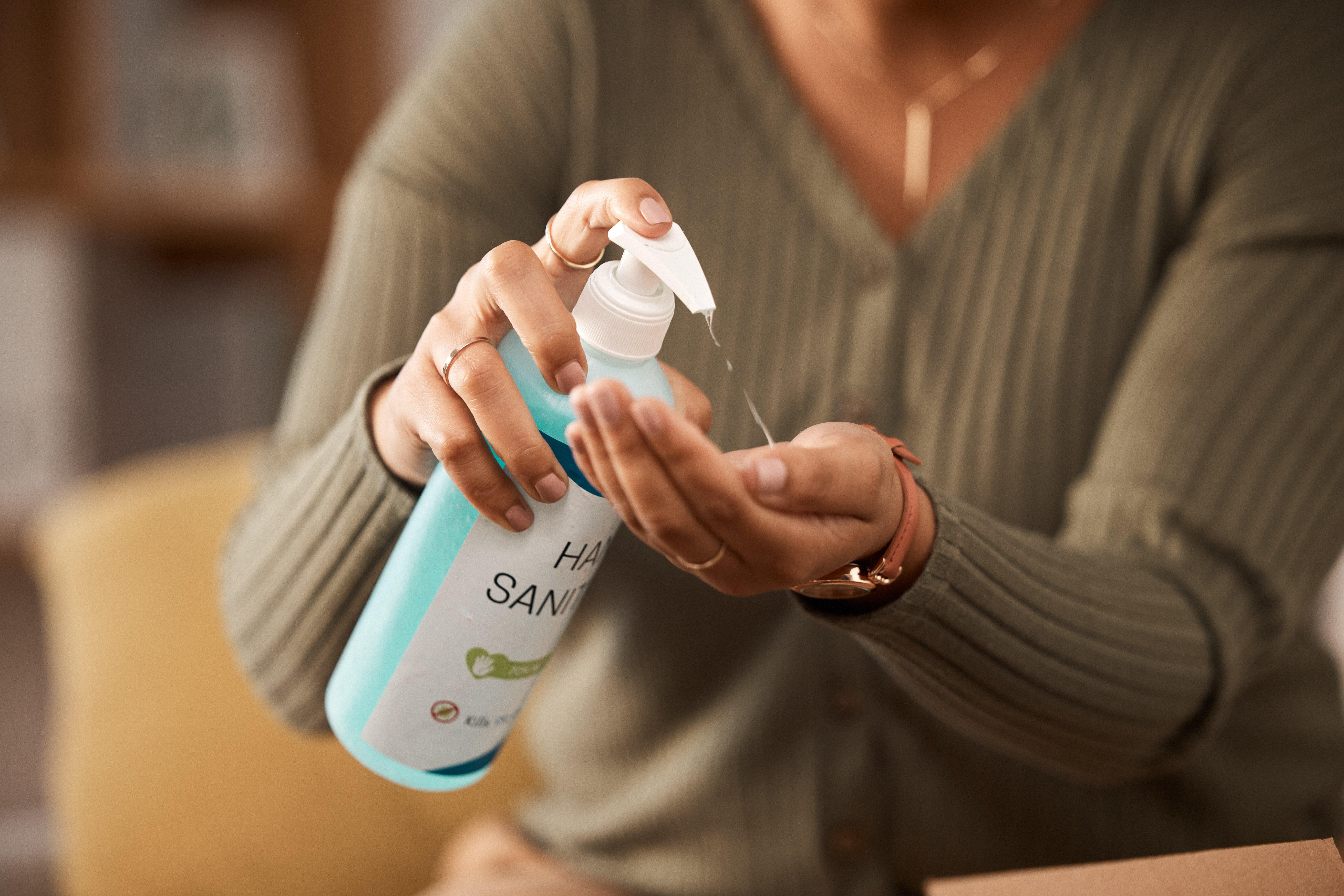 A woman in an office squirts hand sanitizer onto her left palm.
